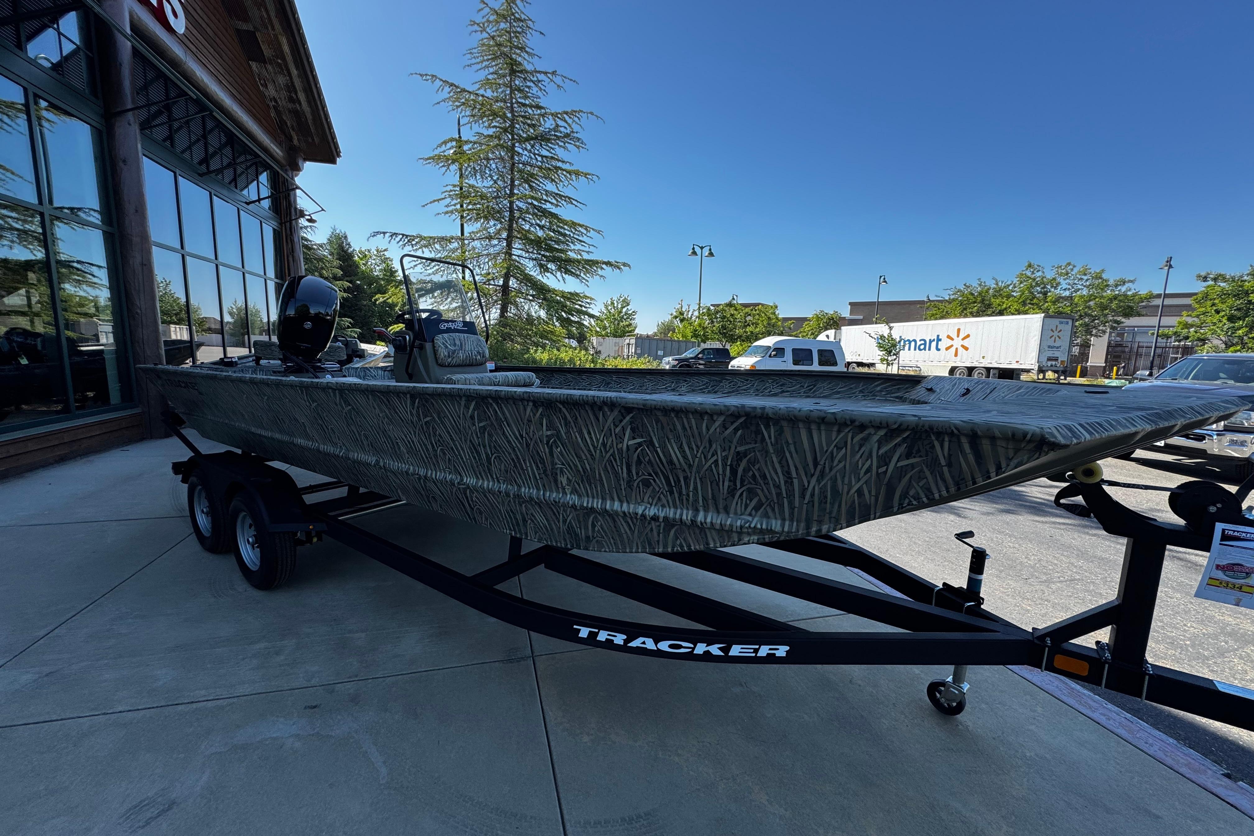 2026 Tracker Grizzly 2072 CC boat on trailer, parked outside a store.