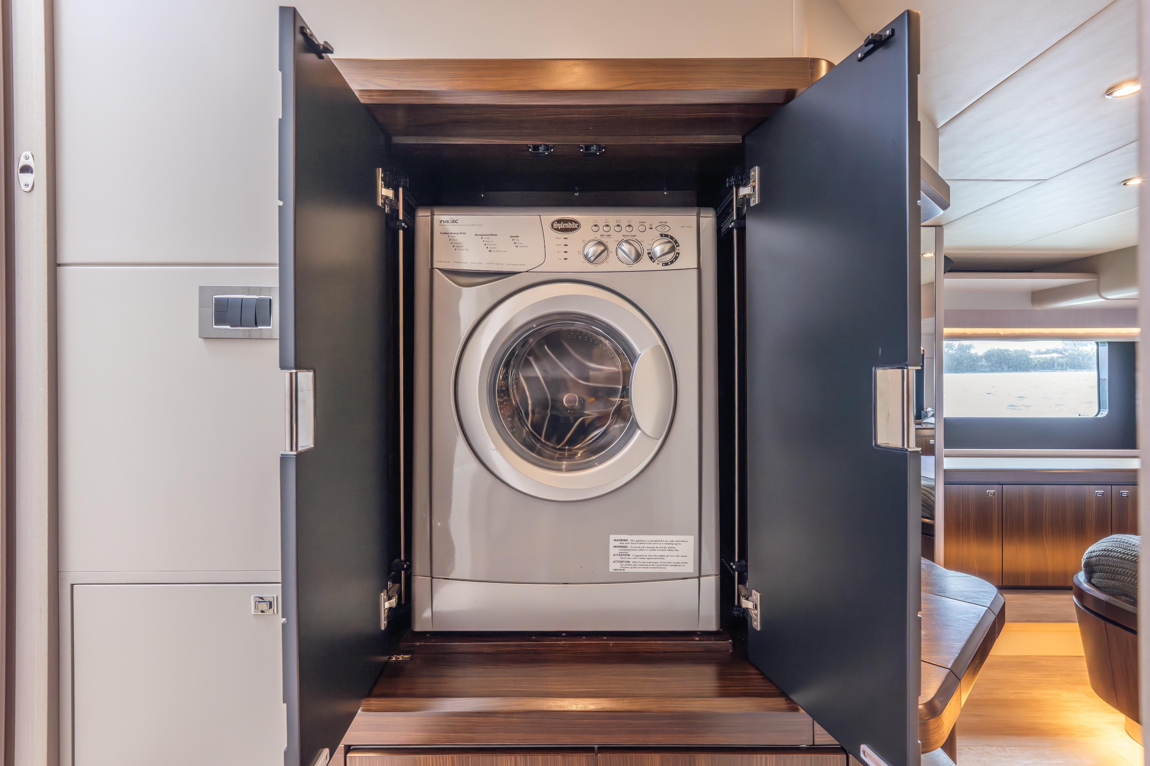 Washing machine inside Absolute 58 FLY yacht, 2019 model, with open cabinet doors.