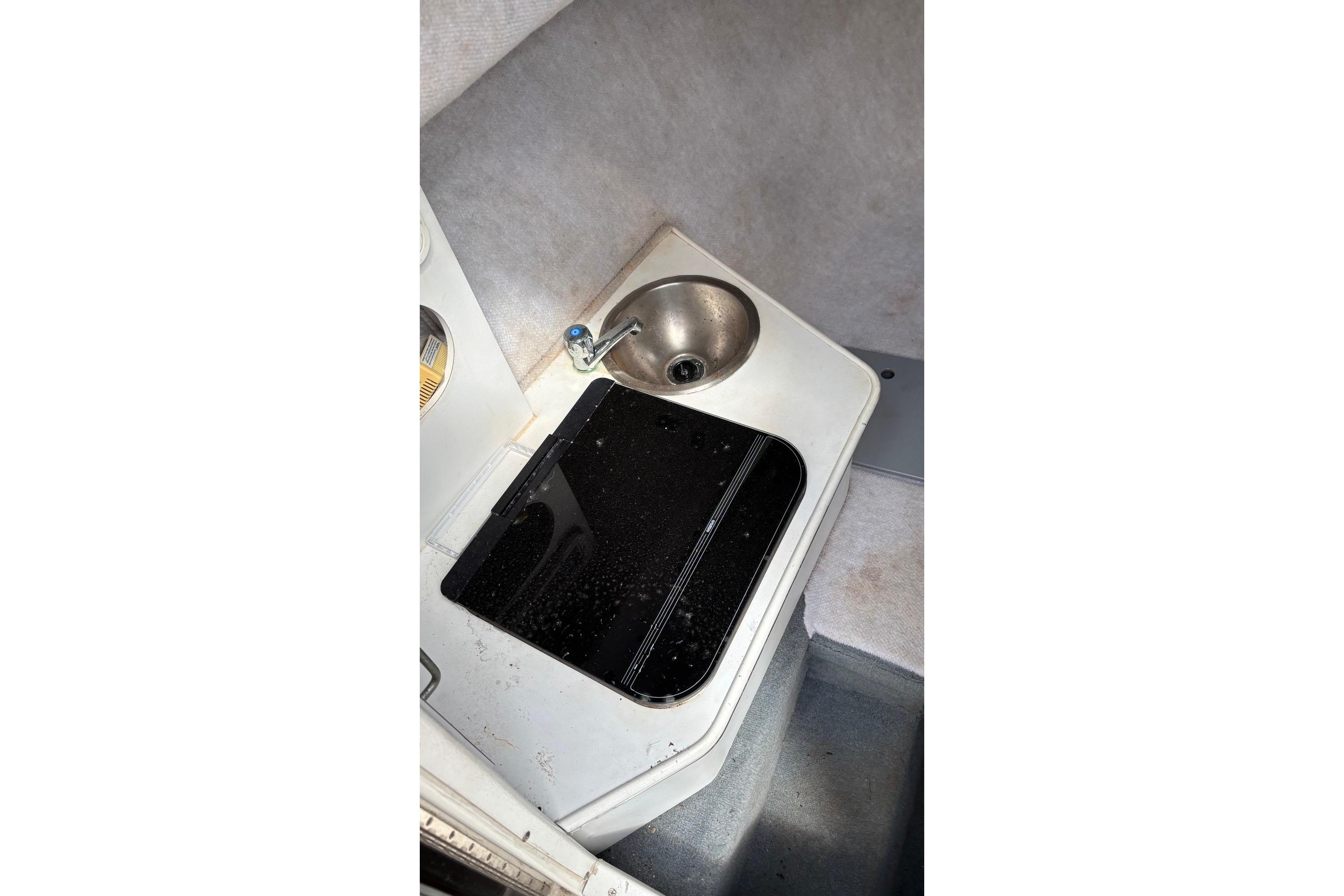 2002 Wellcraft 24 Walkaround boat interior with sink and stove.