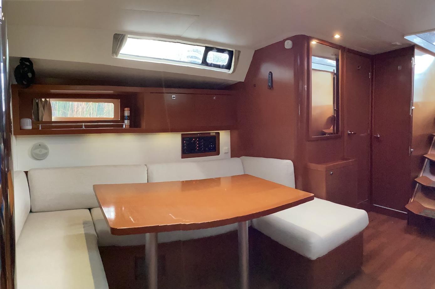 Interior of 2012 Beneteau Oceanis 45 yacht with cozy seating and wooden table.