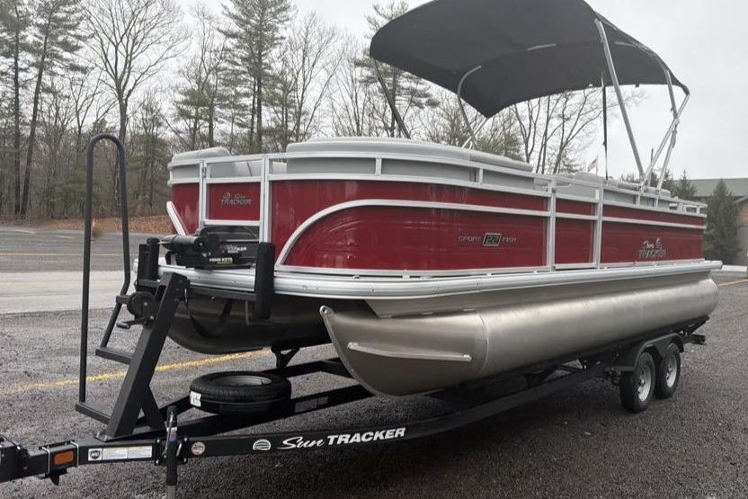 2026 Sun Tracker SportFish 22 DLX pontoon boat on trailer, parked outdoors.