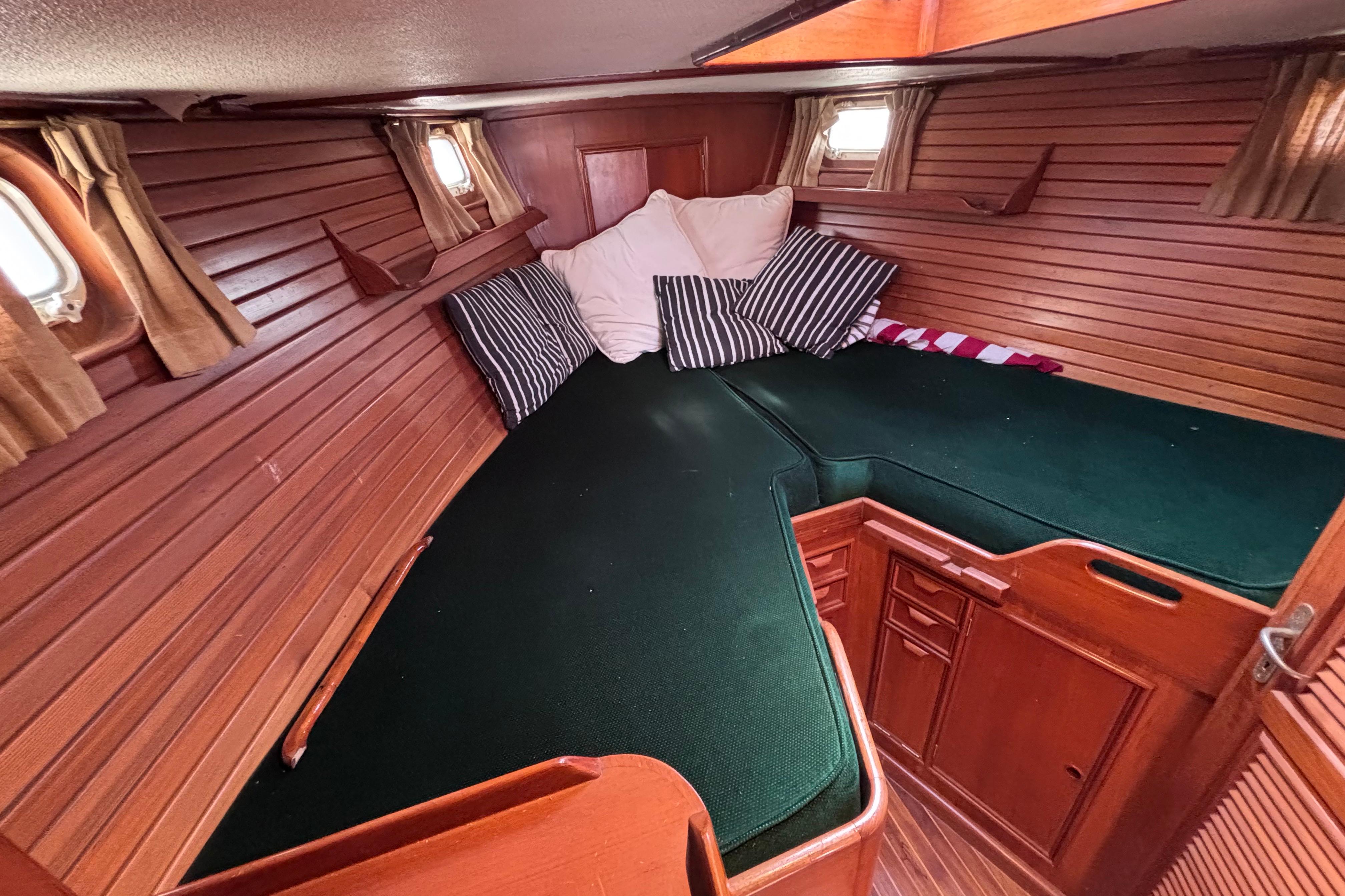 Cozy cabin interior of 1978 Swift 33 sailboat with green cushions and striped pillows.