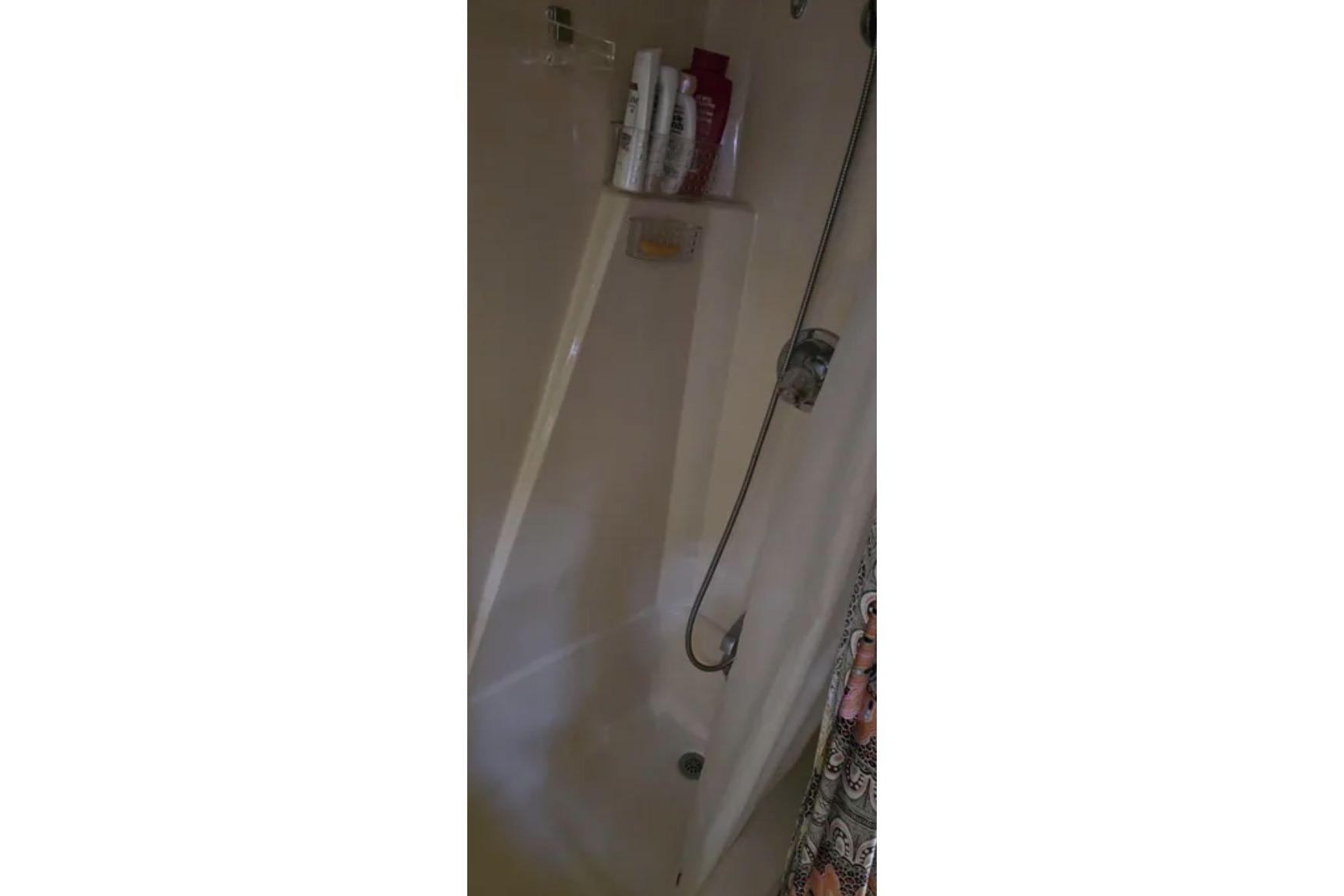 Shower area inside 1987 Chris-Craft 427 Catalina boat with toiletries and curtain.