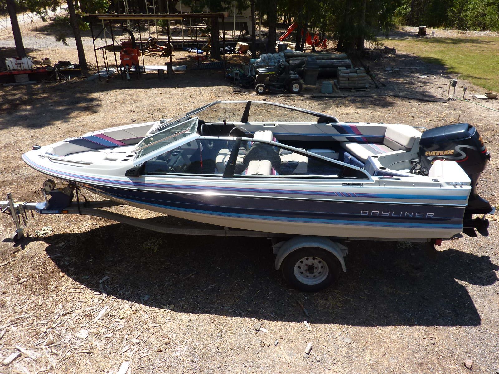 A 1989 Bayliner CAPRI on a trailer in a wooded area.