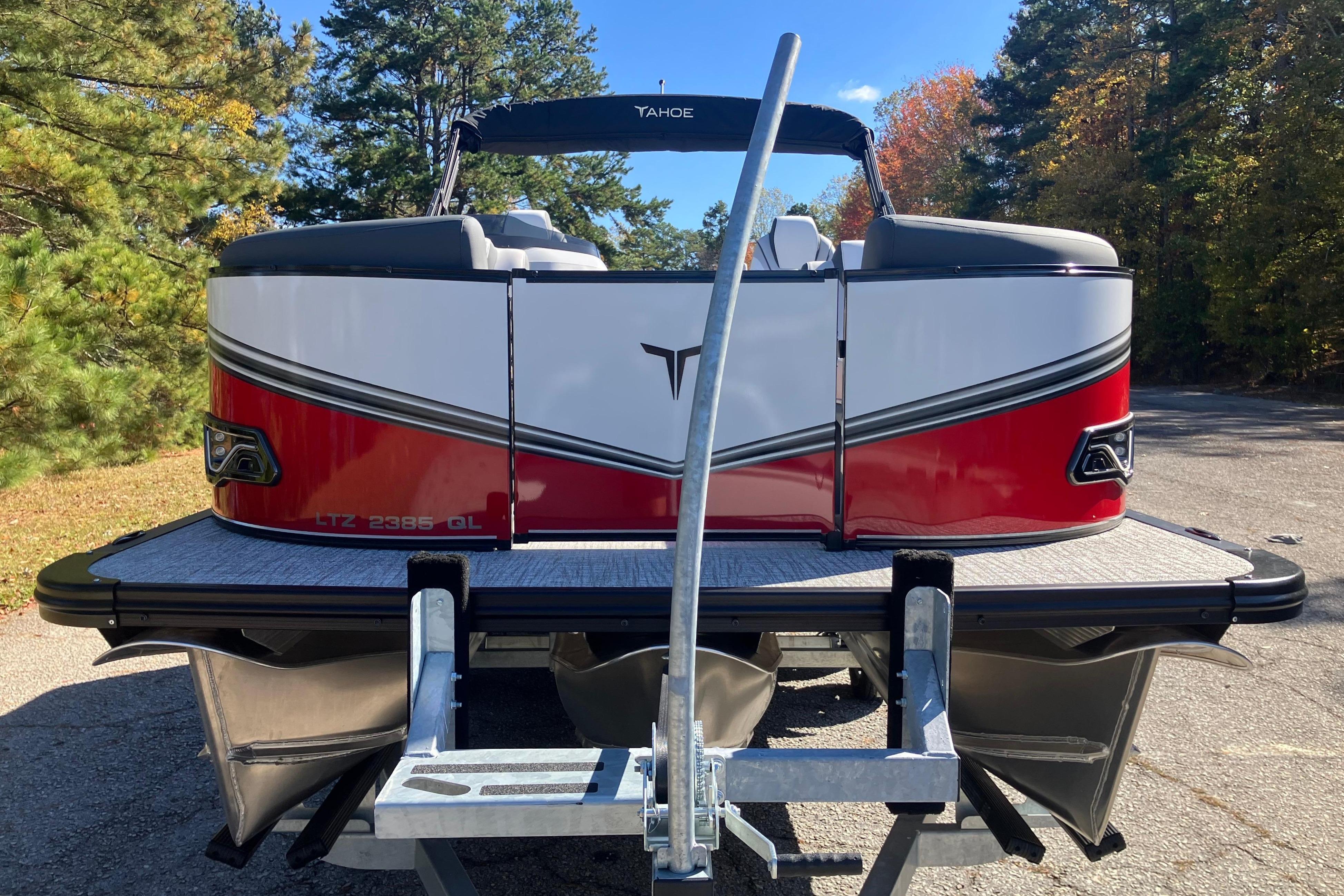 2026 Tahoe Pontoon LTZ Quad Lounger, red and white, parked on a trailer, surrounded by trees.