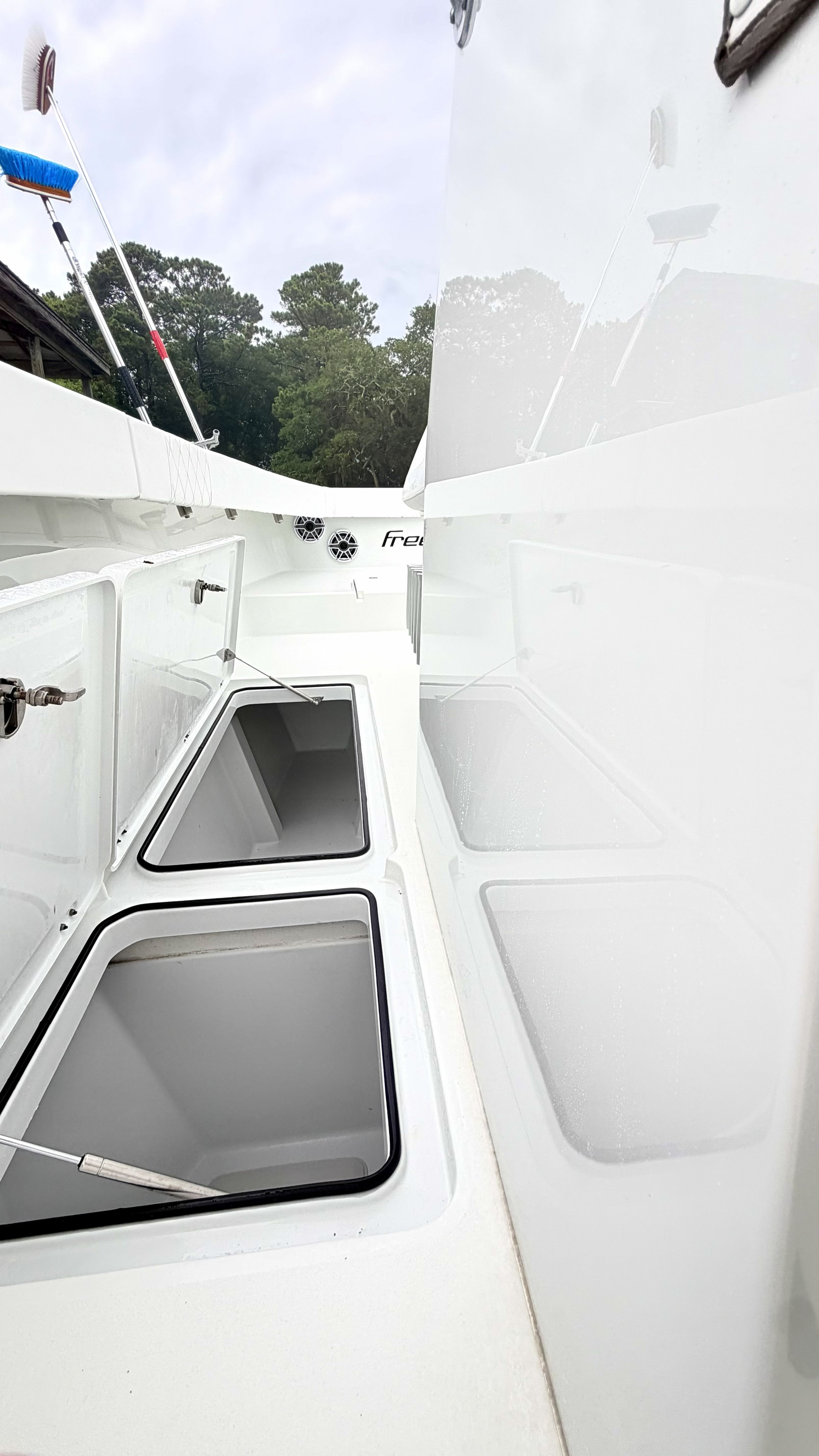 The 2018 Freeman 34VH features open storage compartments on deck, surrounded by trees in the background.