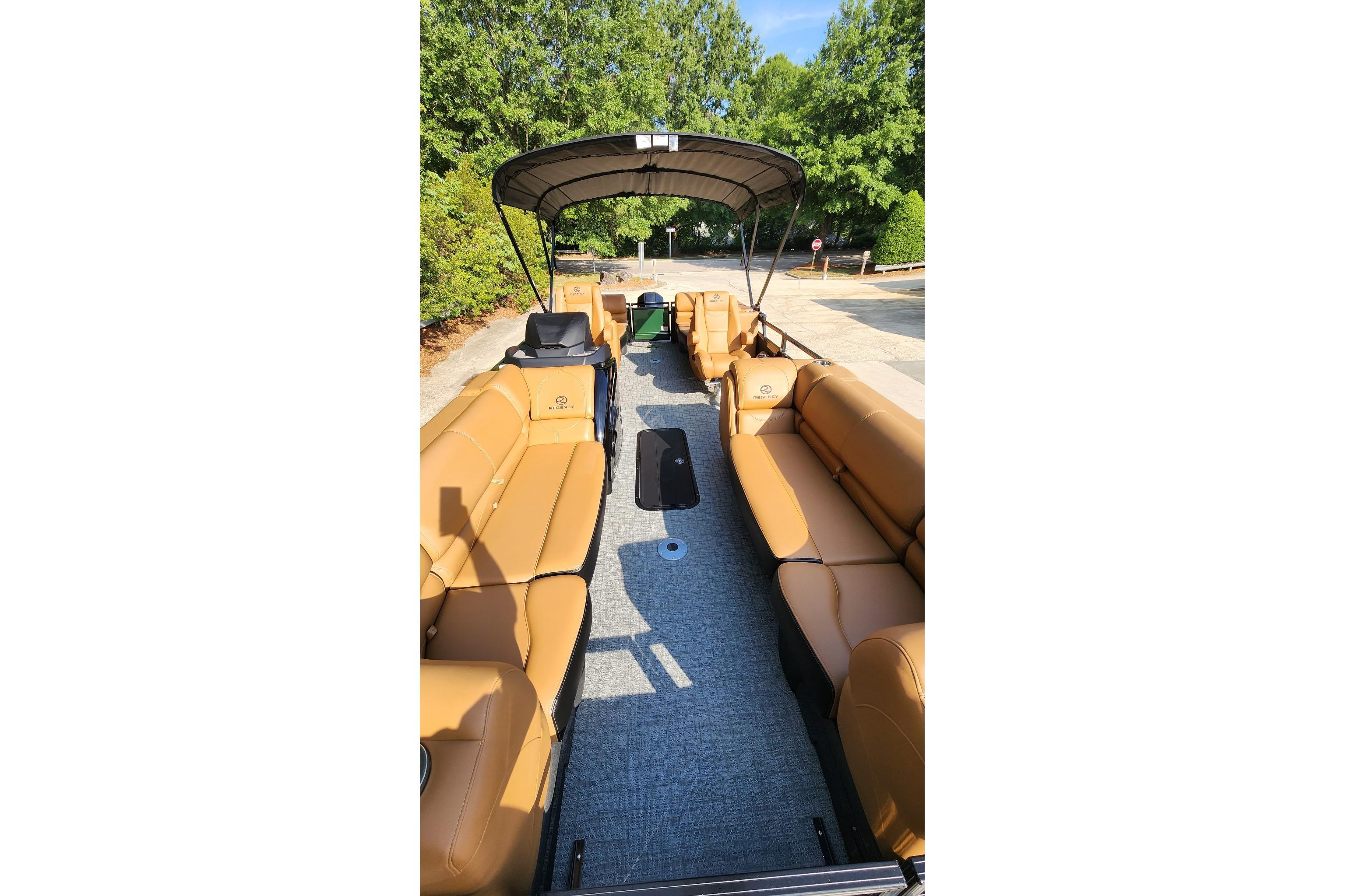 2026 Regency 230 DL pontoon boat with tan seating and canopy, parked outdoors.