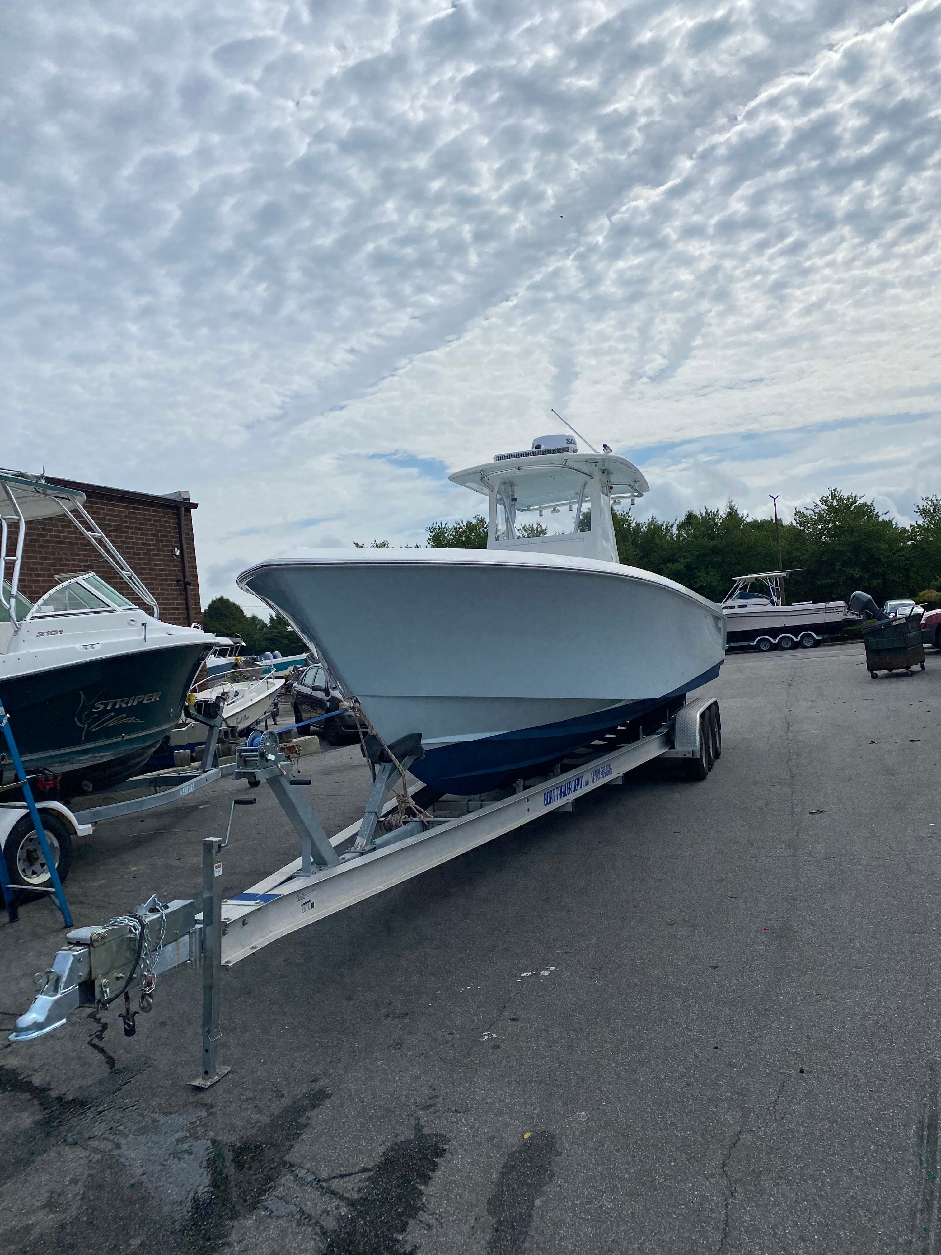 2009 Contender 33 Tournament boat on trailer under cloudy sky.