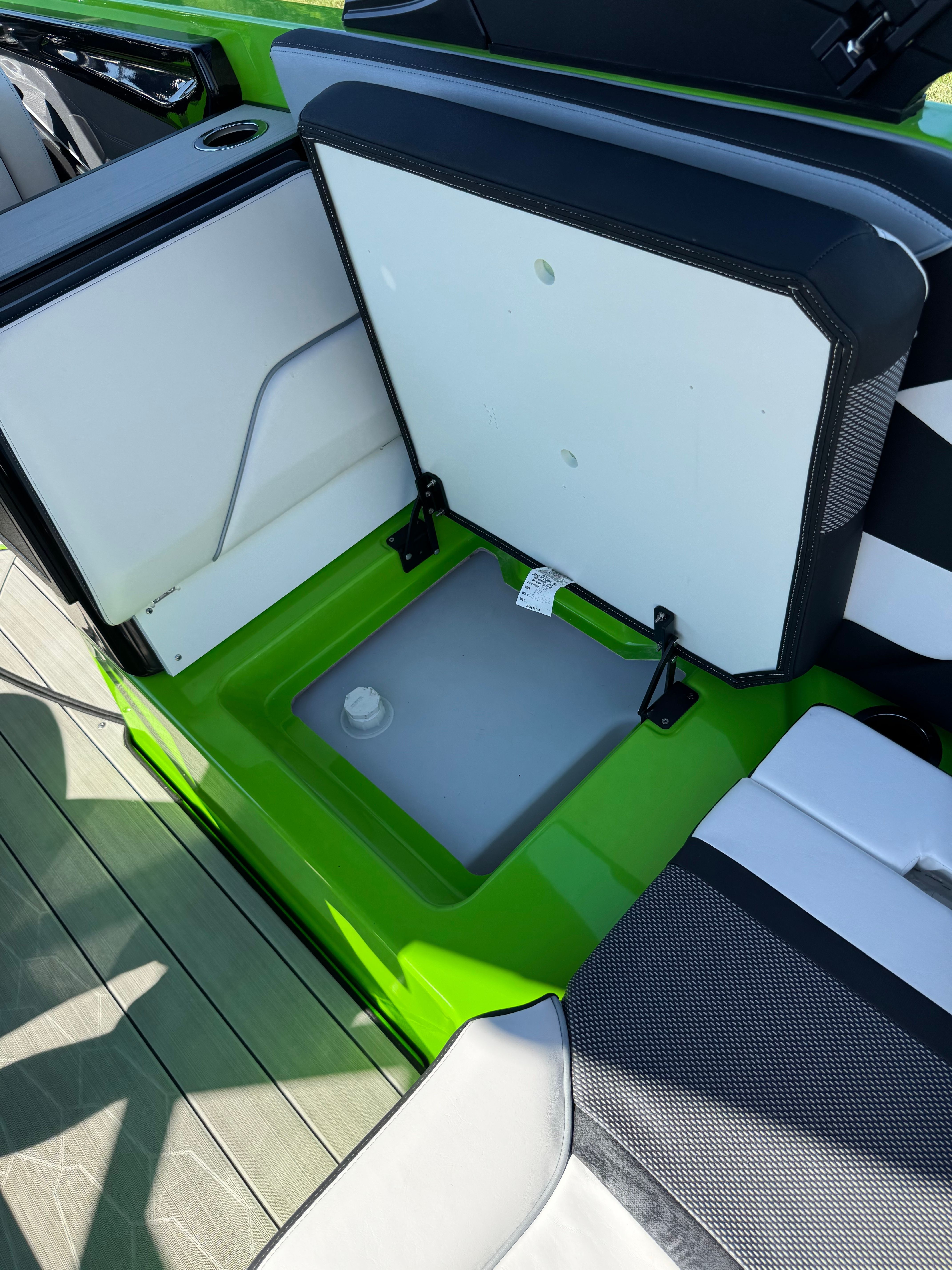An open storage compartment on a green boat with black and white seating.