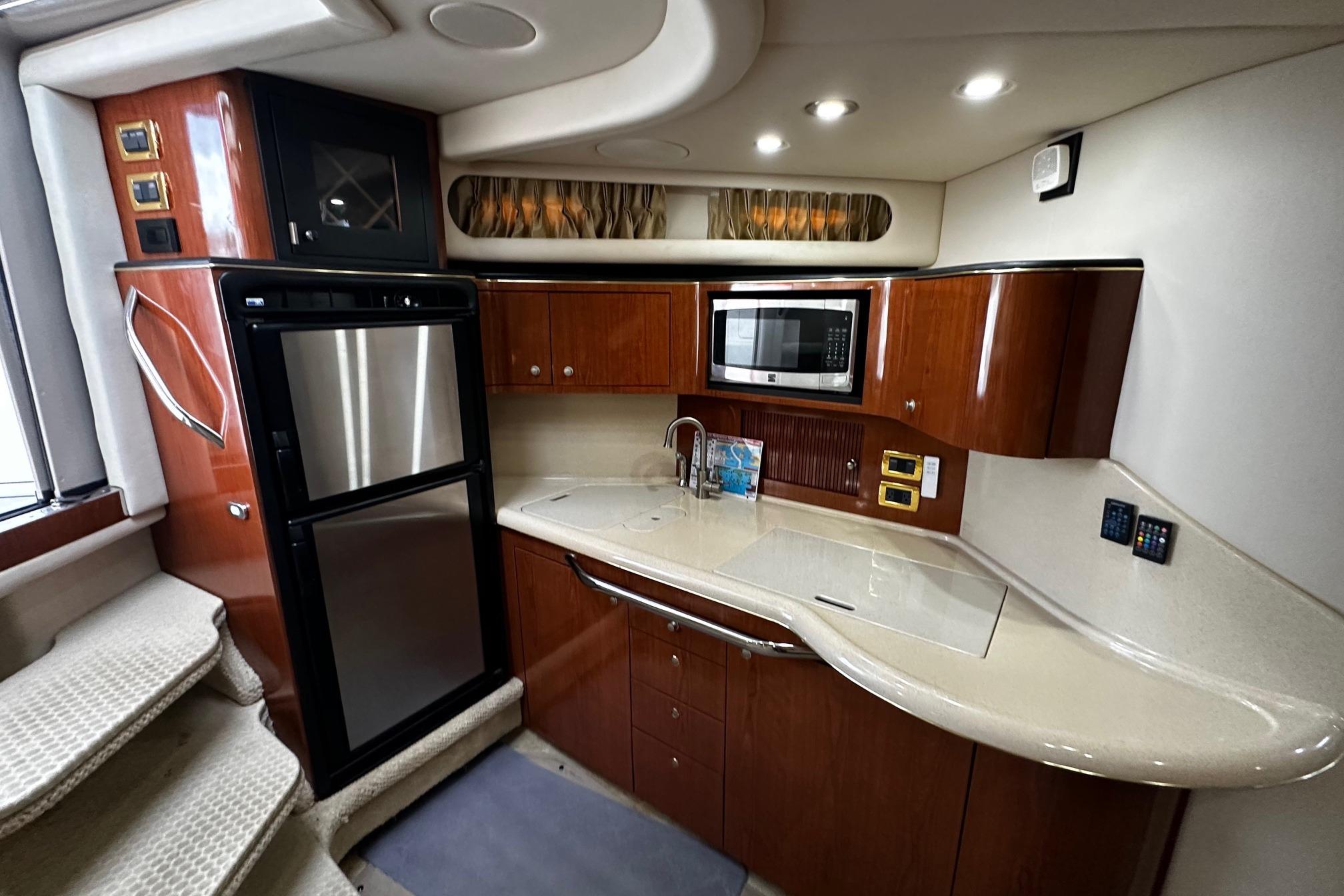 Luxurious 2001 Sea Ray 380 Sundancer yacht kitchen with modern appliances and elegant wood cabinetry.