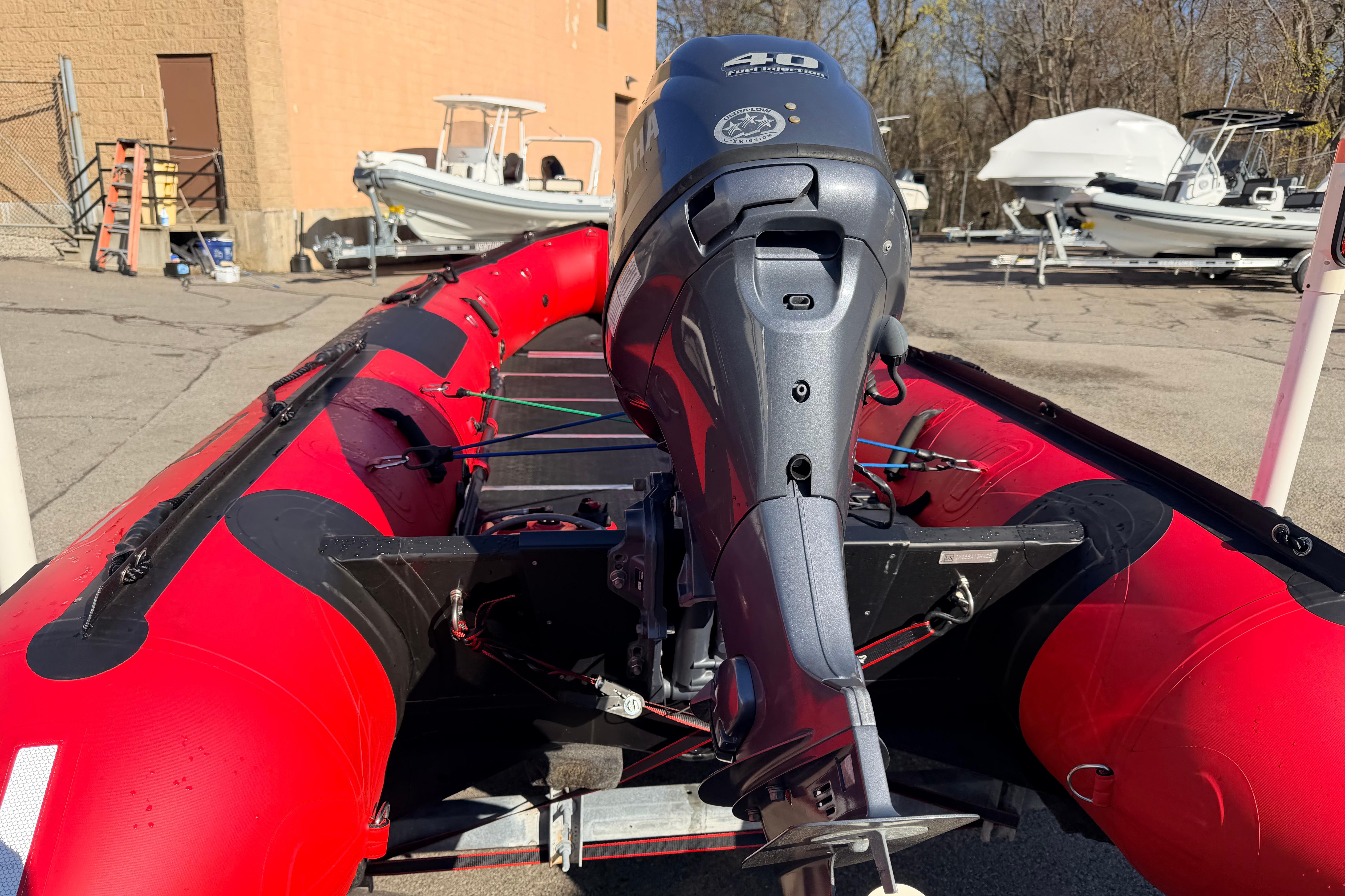 Red 2025 Inmar 530RHD inflatable boat with outboard motor in a parking lot.