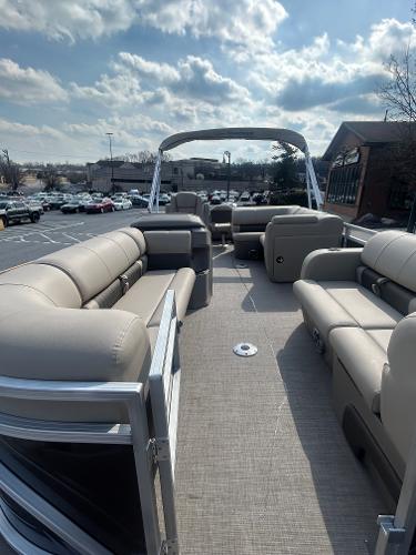 2025 Sun Tracker SportFish 22 DLX pontoon boat with spacious seating and canopy, parked outdoors.