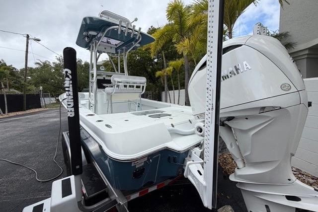 2025 Contender 26 Bay boat with Yamaha engine, parked on a trailer near palm trees.