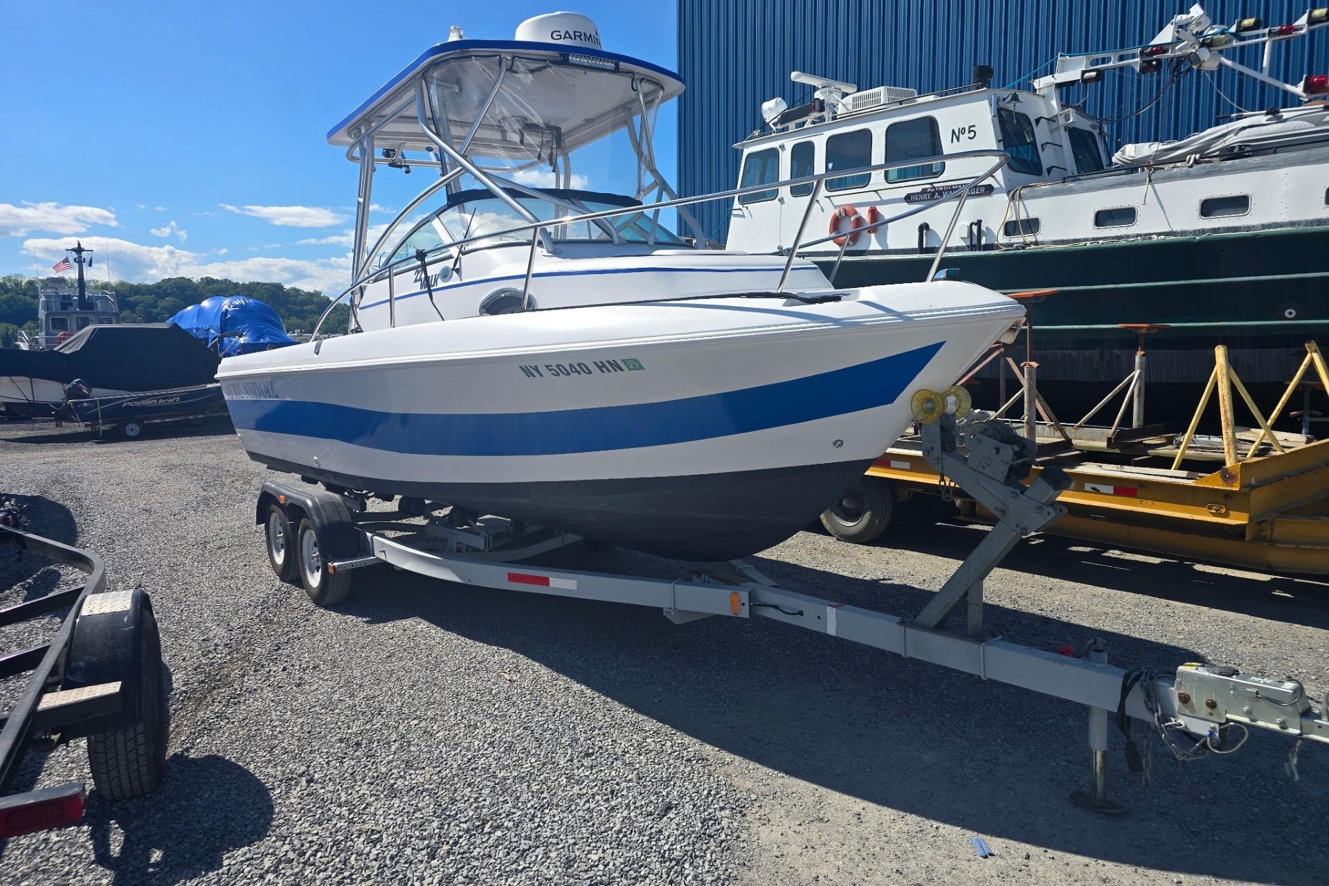 2003 Pro-Line 22 Walkaround boat on trailer, parked outdoors under clear sky.
