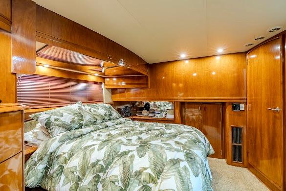 Luxurious bedroom interior of 2003 Carver 570 Voyager Pilothouse yacht with wood paneling.