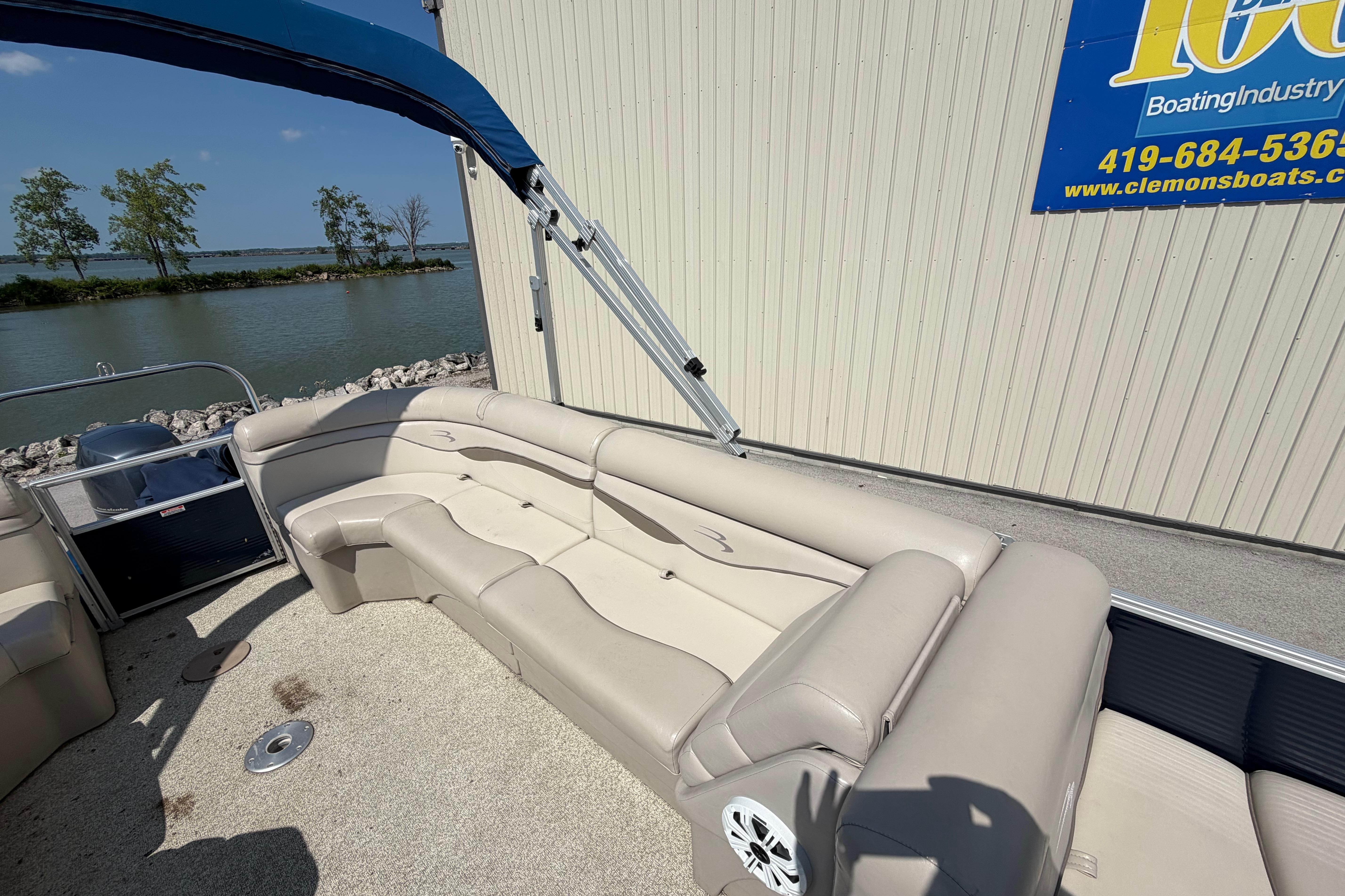 2017 Bennington 25 SSXAPG pontoon boat with beige seating, docked by a lake.