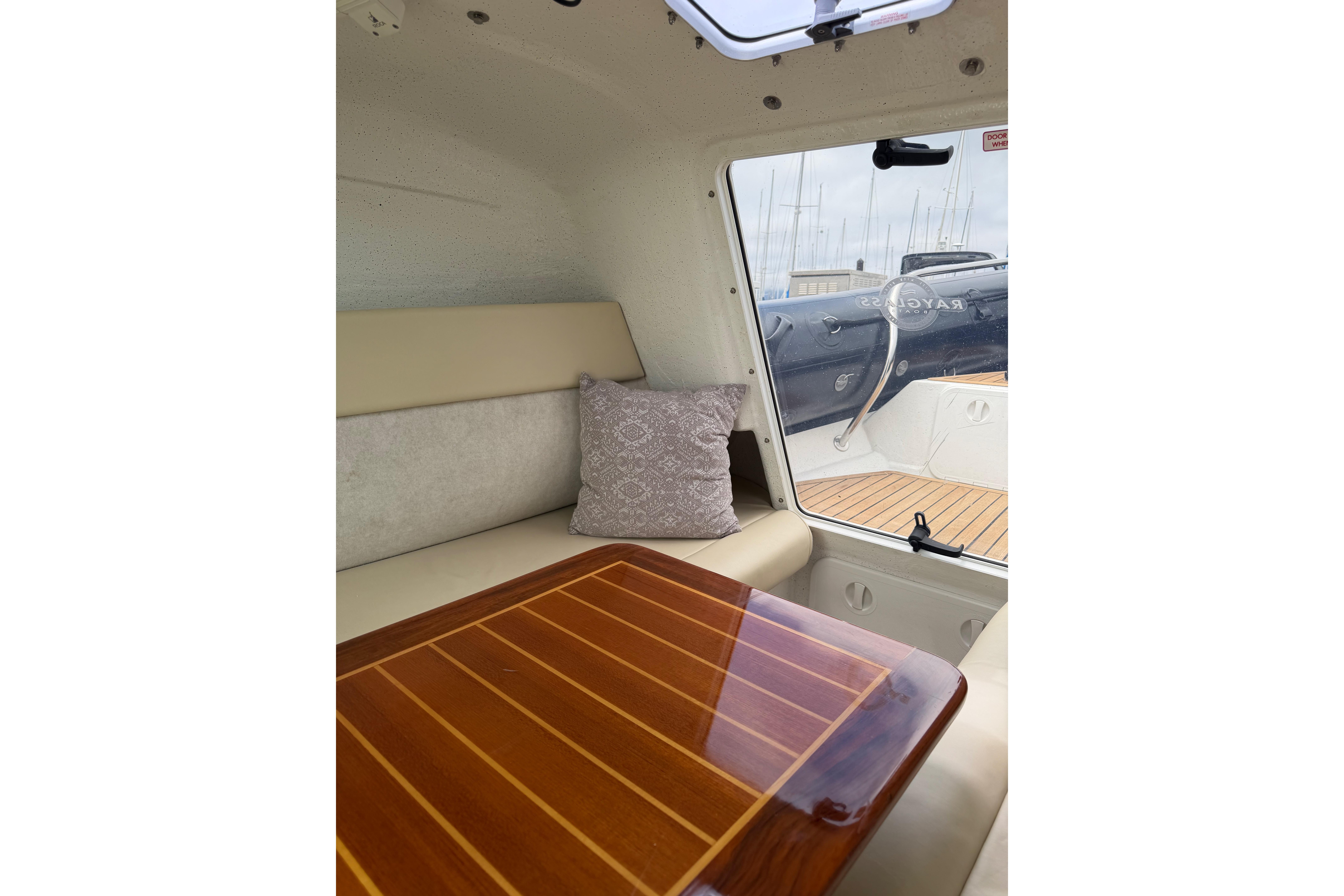 Interior of 2016 Protector Targa 30 boat with wooden table and cushioned seating.
