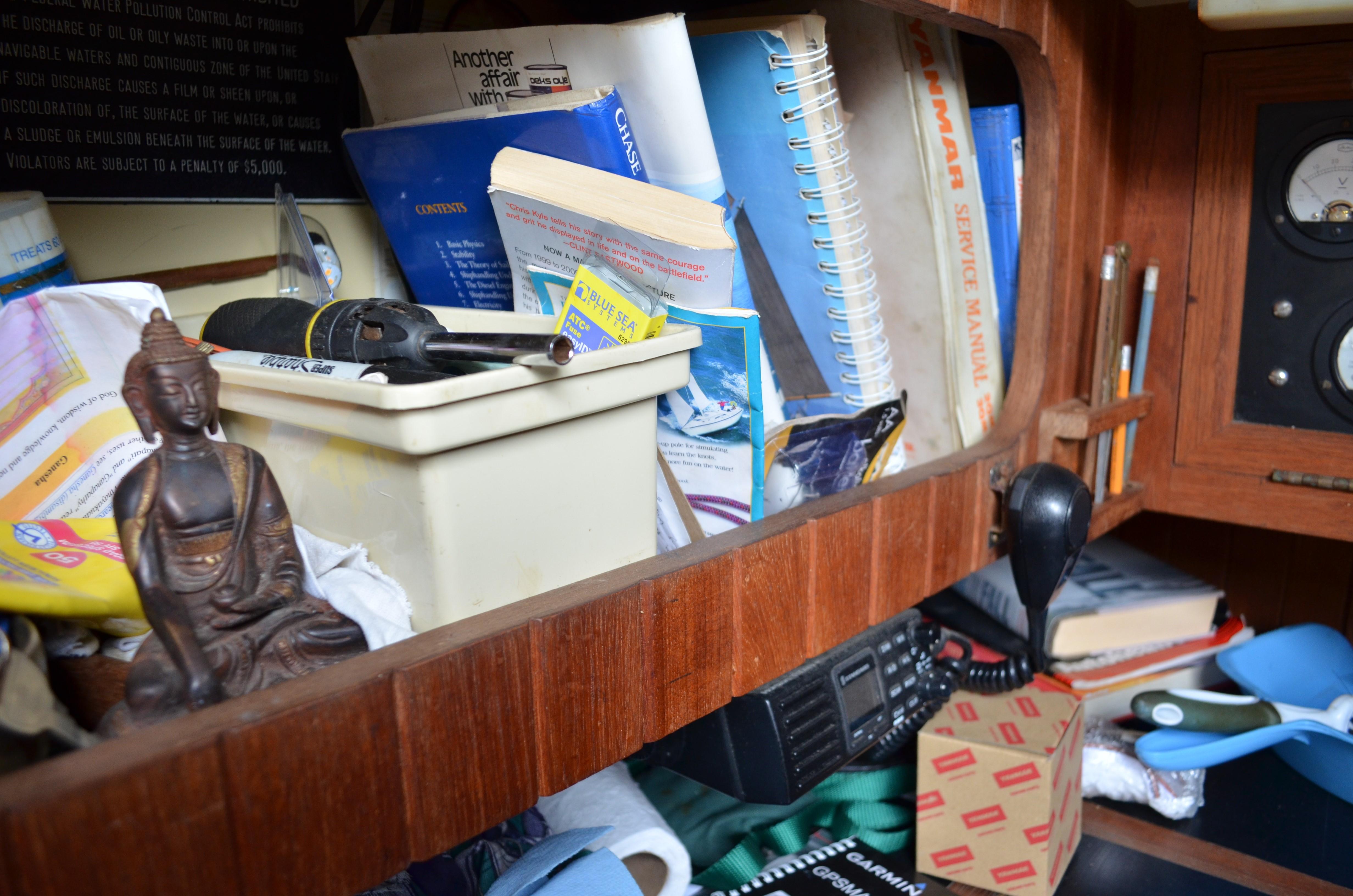 Interior of 1982 Young Sun Cutter with books, tools, and a Buddha statue on a wooden shelf.