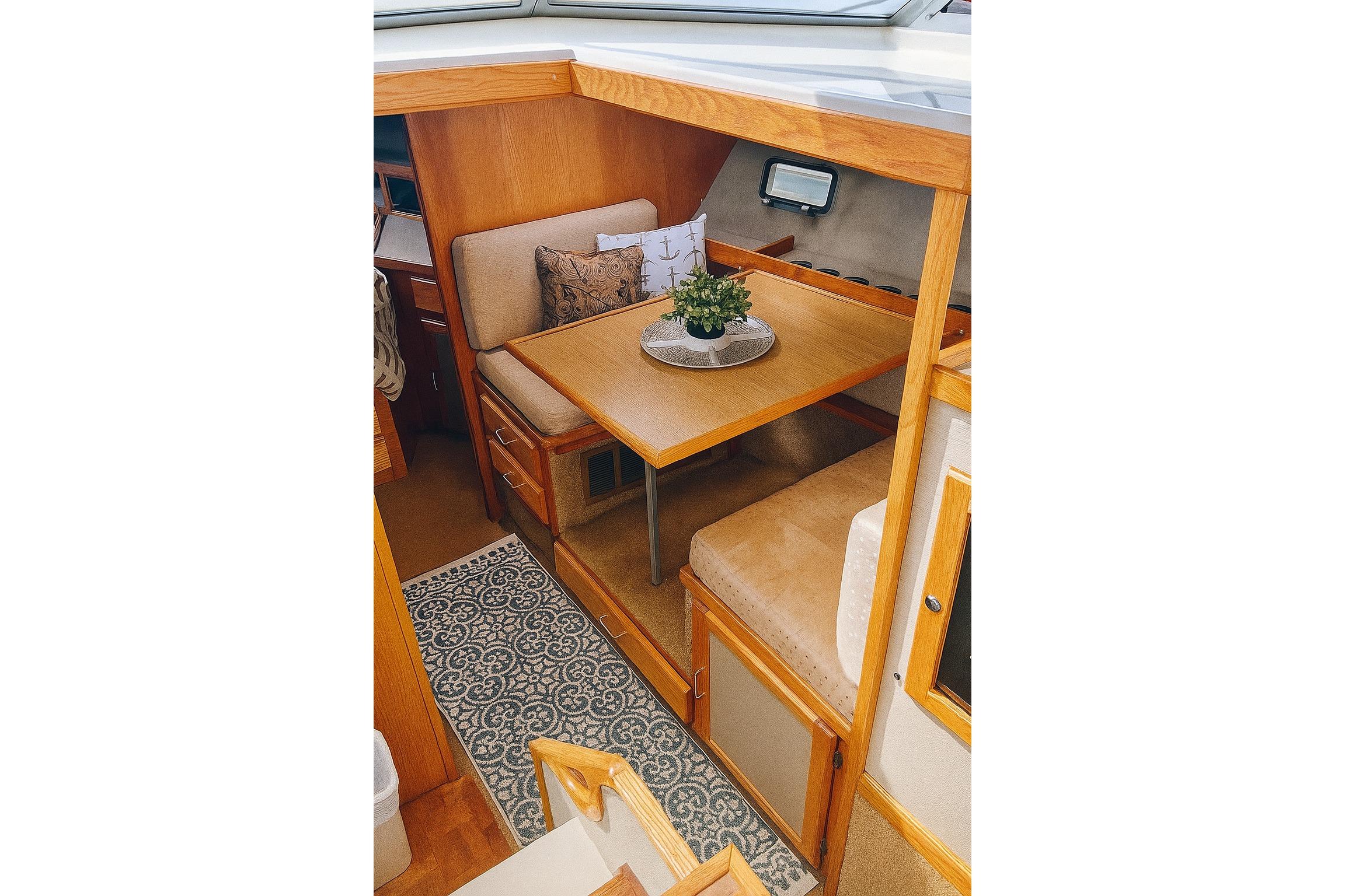 Interior of 1985 Silverton 34 Convertible yacht with cozy dining area and wooden accents.