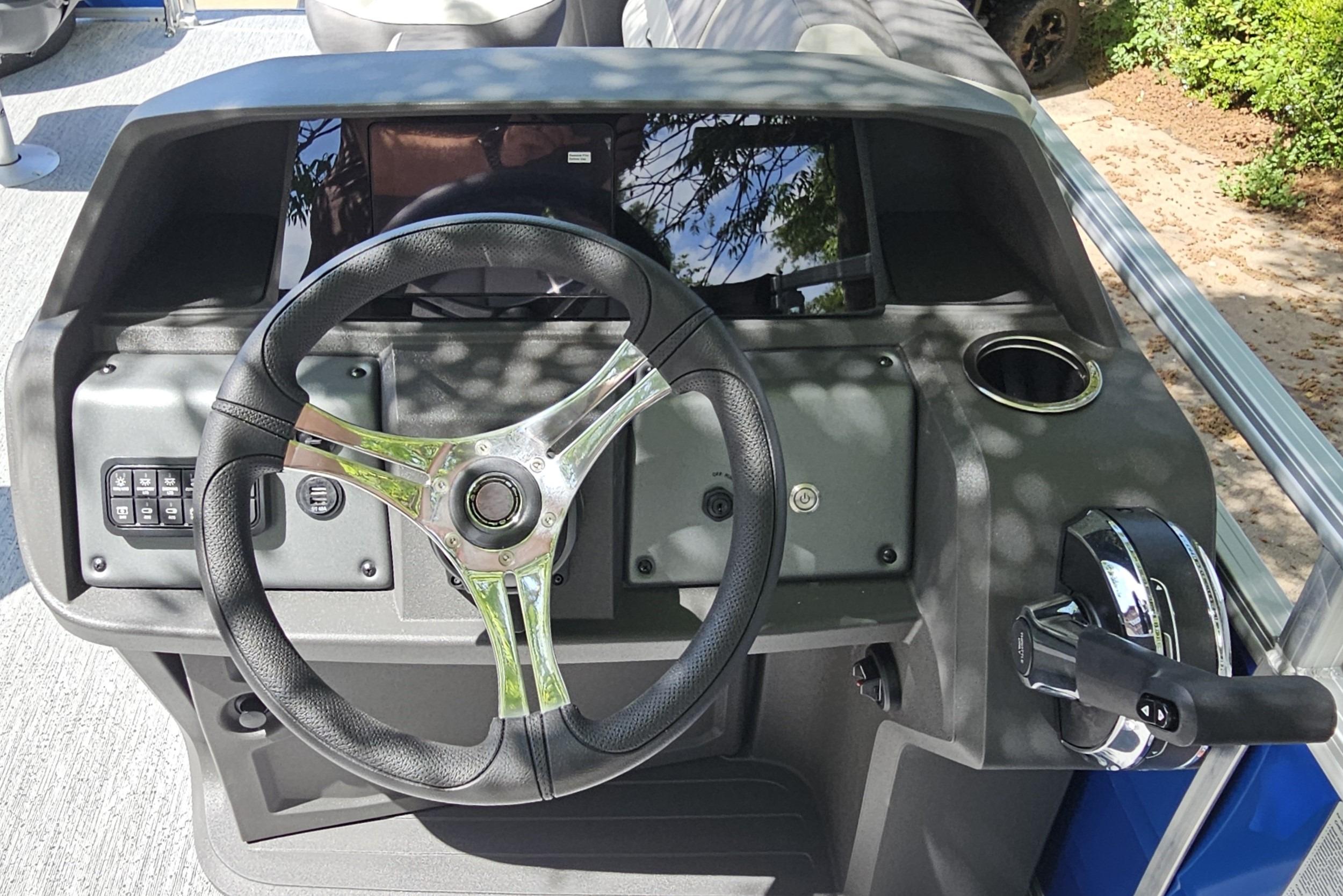 2026 Sun Tracker Fishin' Barge 20 DLX steering console with controls and cup holder.