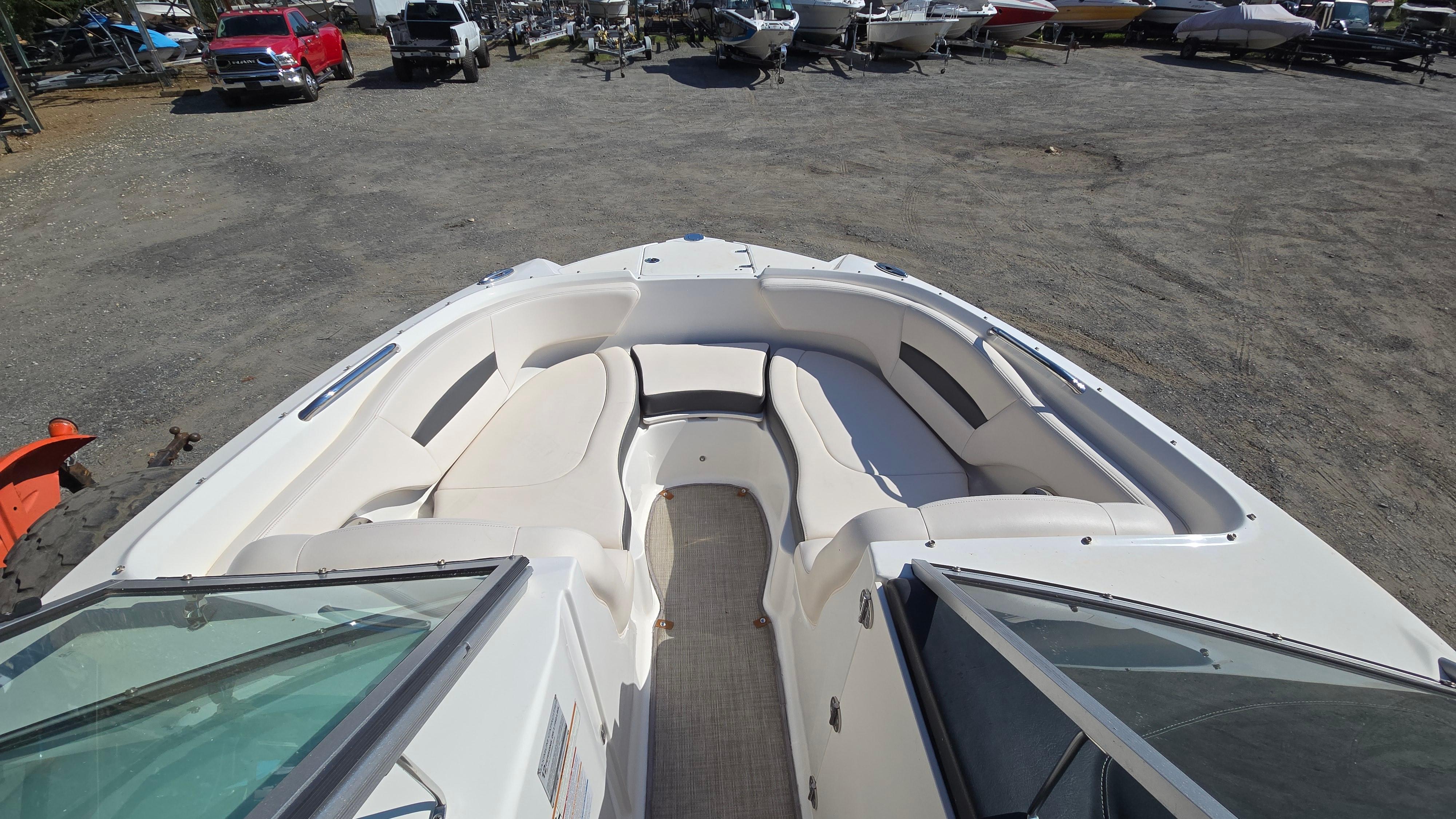2018 Chaparral 224 Sunesta boat with spacious seating, parked in a boatyard.