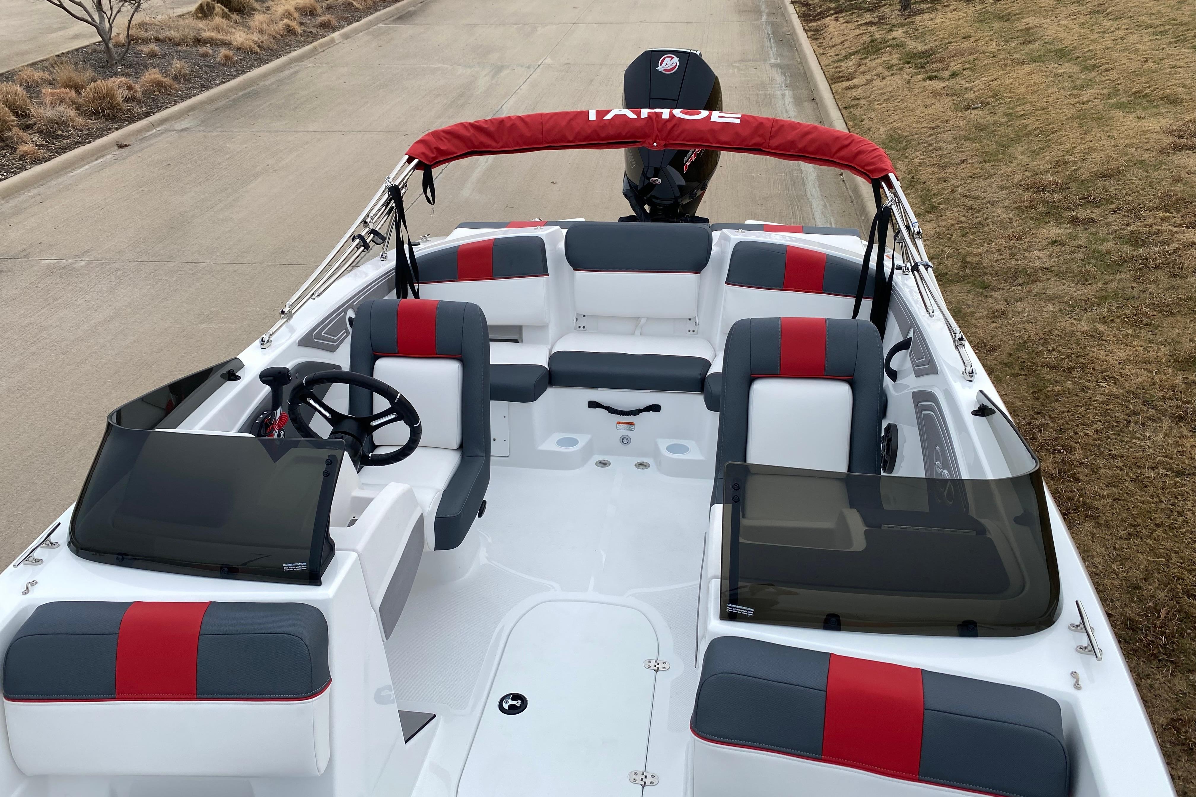 2026 Tahoe T21 boat interior with red and gray seating, steering wheel, and windshield.