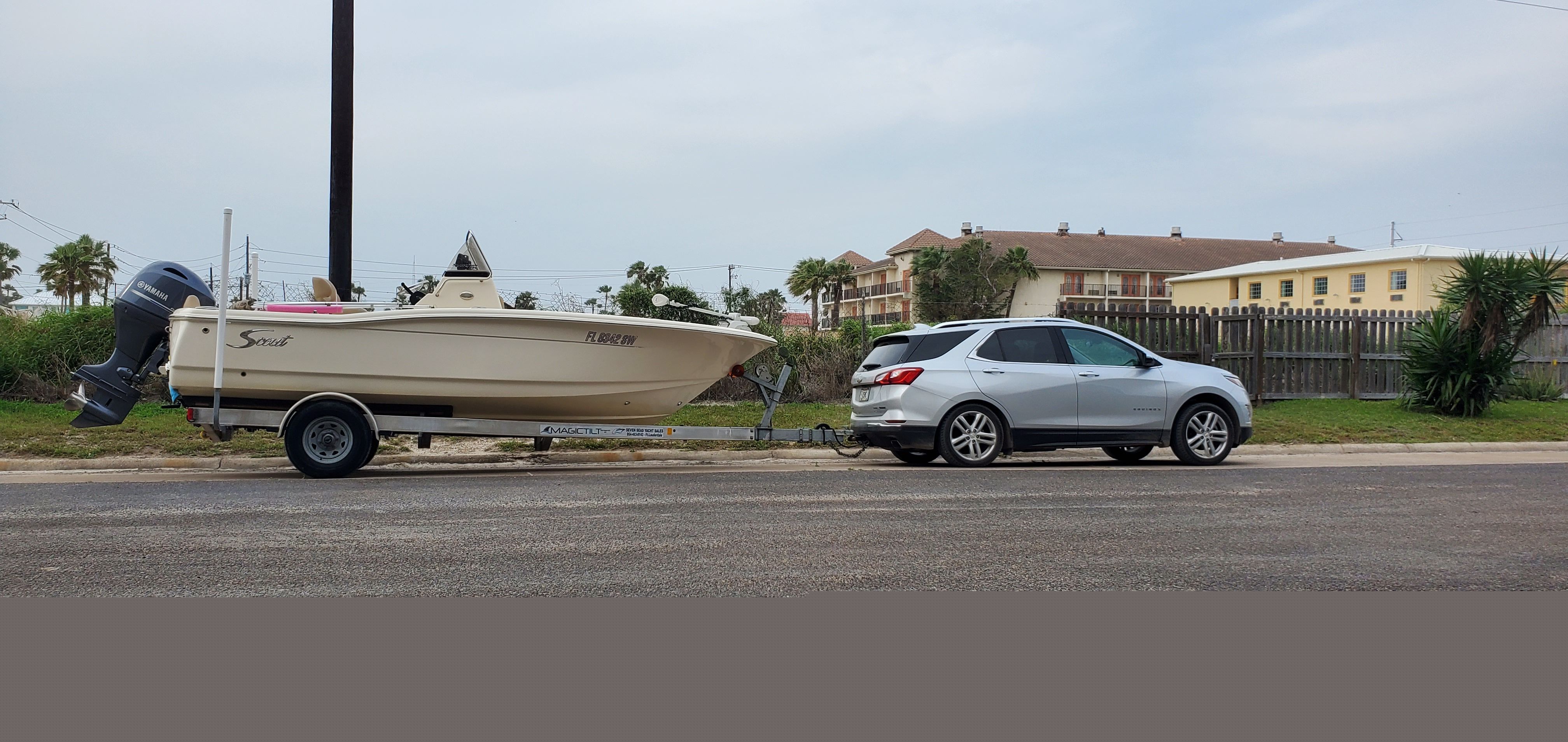 A 2021 Scout 195 Sportfish boat on a trailer, towed by a silver car.