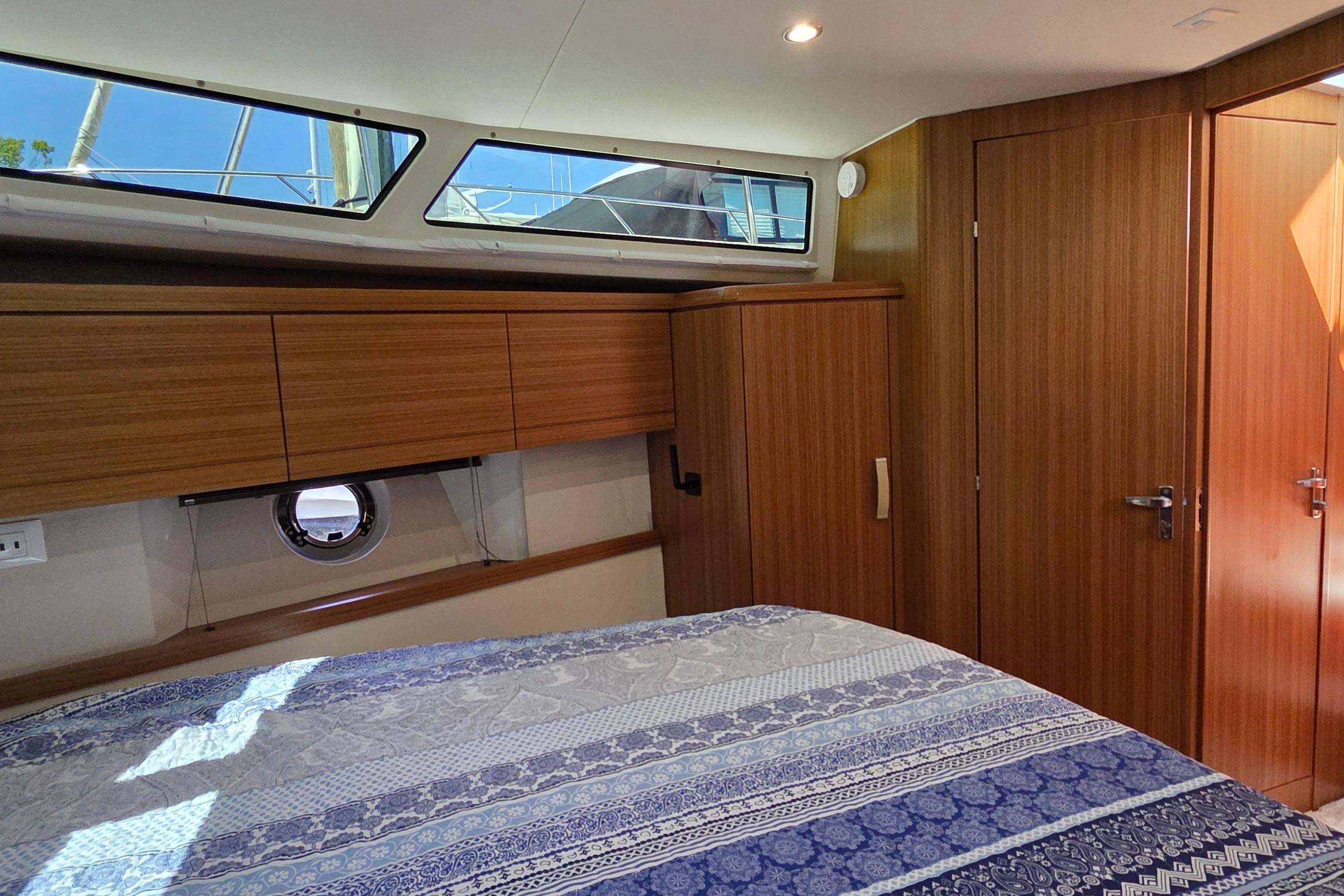 Luxurious cabin interior of 2023 Greenline 40 yacht with wood paneling and patterned bedding.