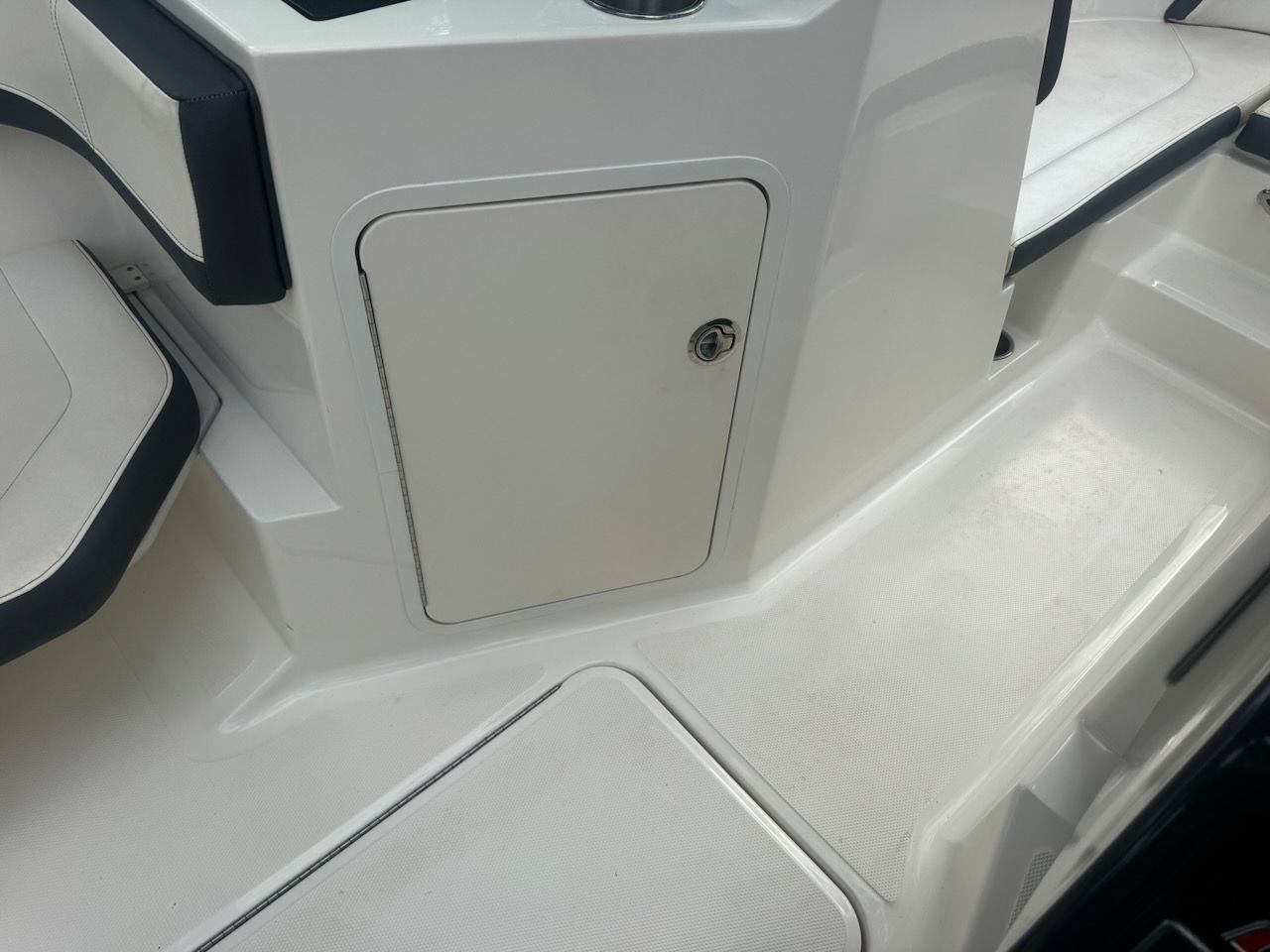 Interior of a Sea Ray SPX 190 Outboard with white seating and storage compartment.