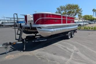 2026 Sun Tracker Party Barge 20 DLX pontoon boat on trailer in parking lot.