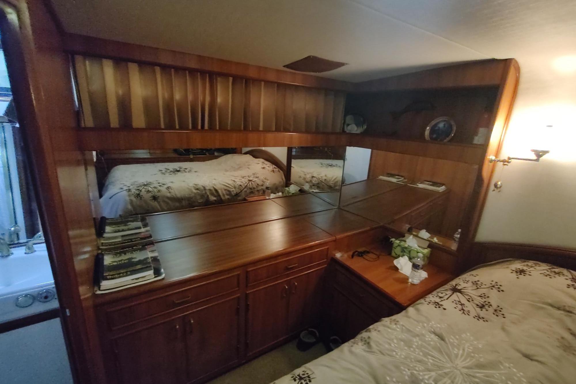 Luxurious 1989 Hyatt Double Cabin Motoryacht bedroom with elegant wood furnishings and mirrored accents.