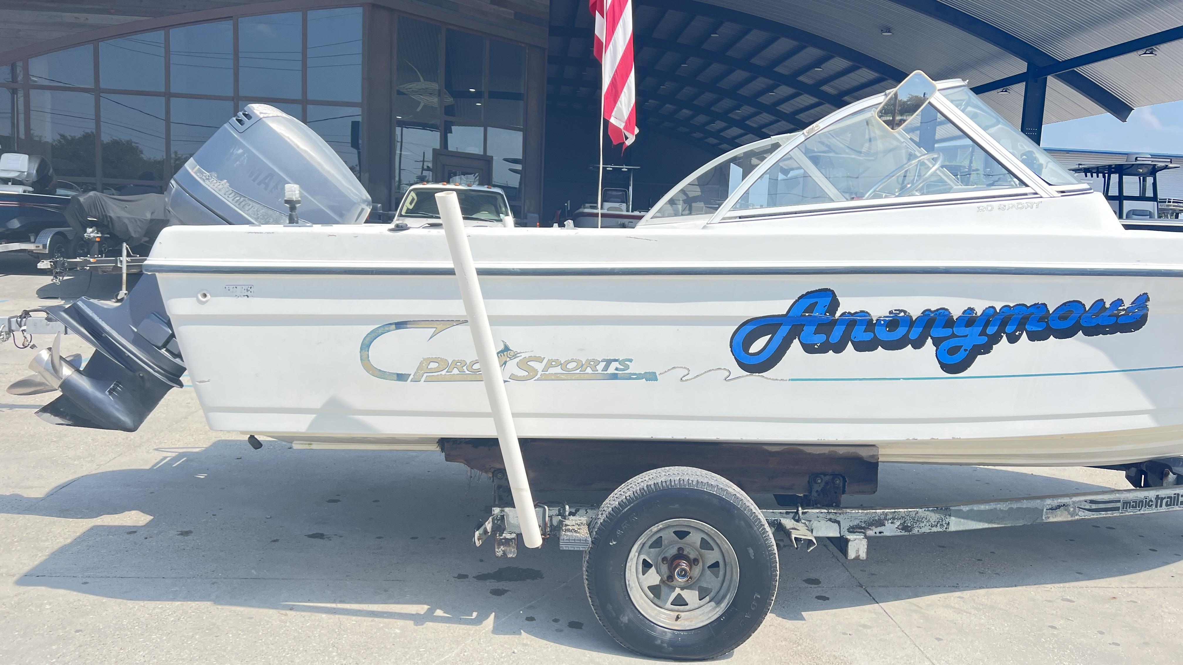1998 Pro Sports Walk Through boat named "Anonymous" on a trailer, parked outside a building.
