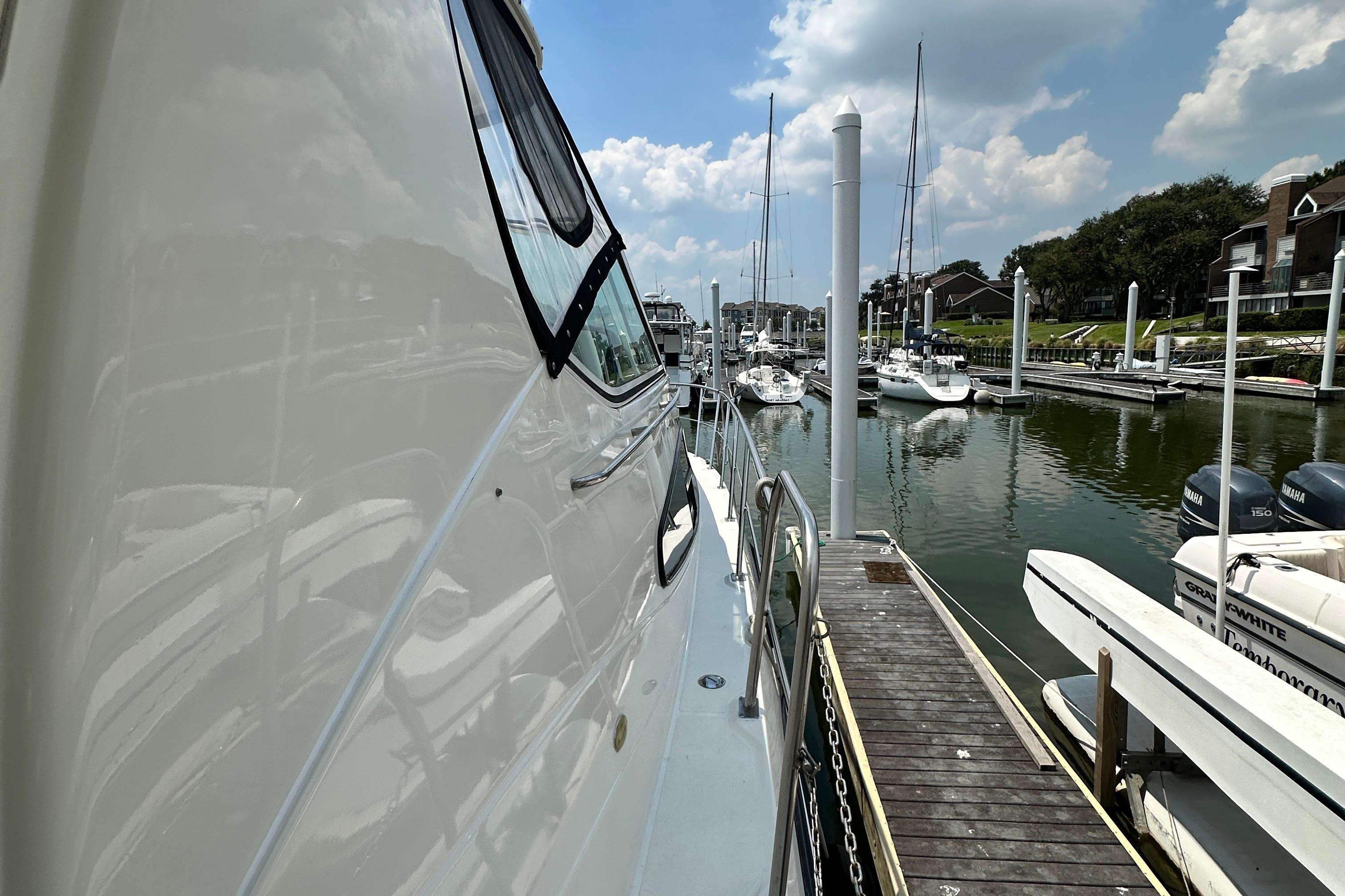 2004 Cruisers Yachts 405 Express Motoryacht docked at marina under blue sky.