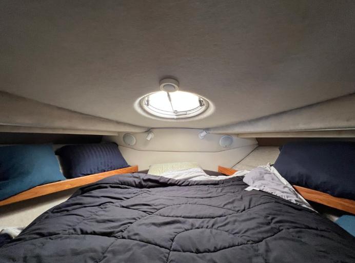 Cozy cabin interior of 1997 Bayliner 3788 Command Bridge Motoryacht with bed and porthole.