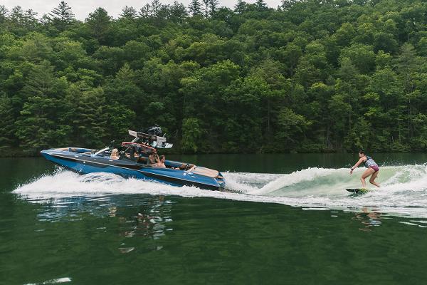 Manufacturer Provided Image: 2021 Axis A24 boat towing a wakeboarder on a lake with forested background.