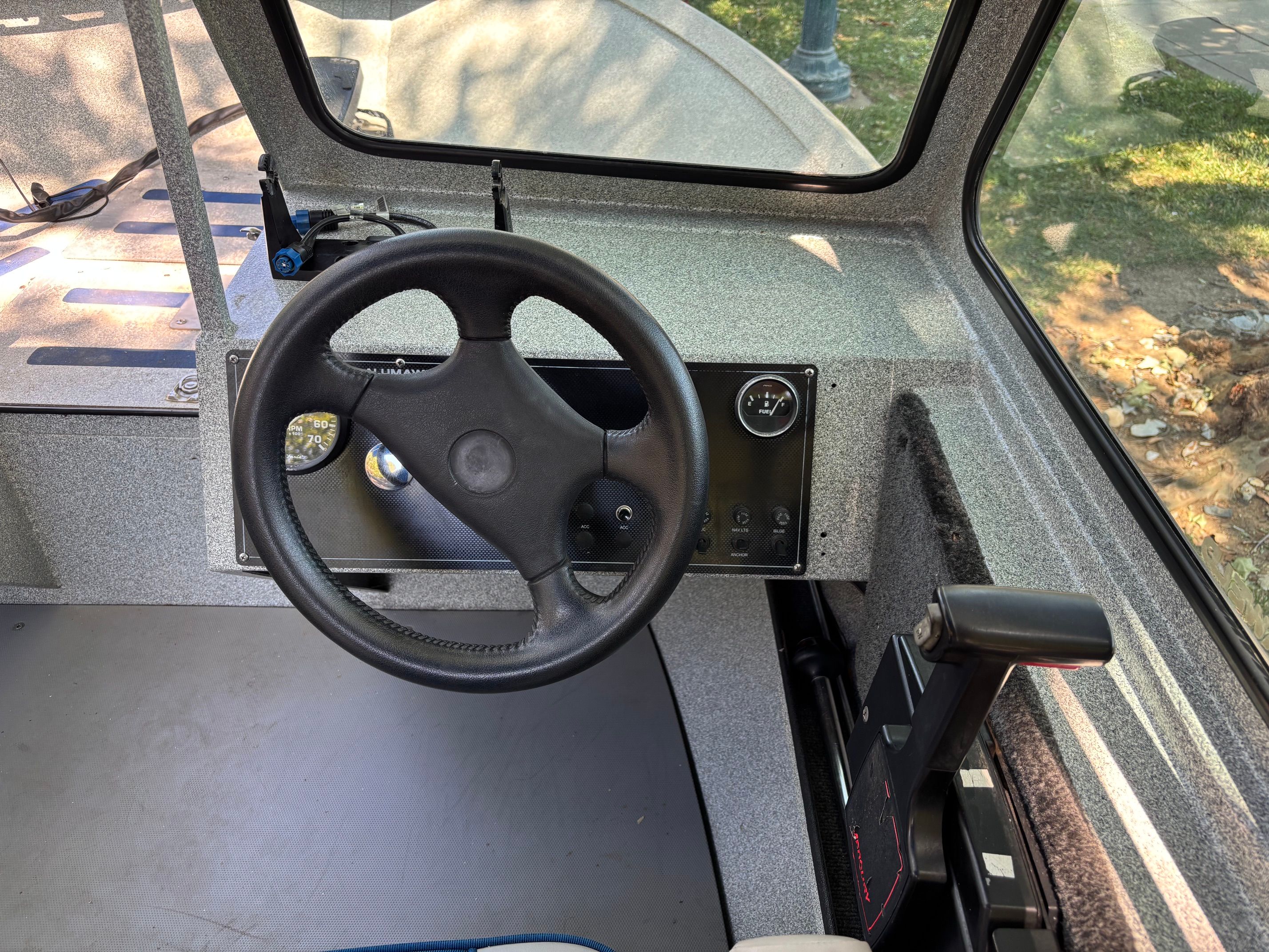 The image shows the cockpit of a 2002 Stryker Rogue boat with a steering wheel and controls.