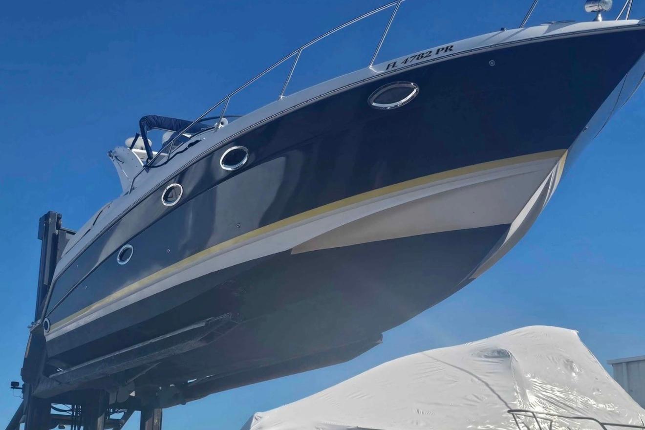 2003 Regal Commodore 3260 boat lifted on a dock under clear blue sky.