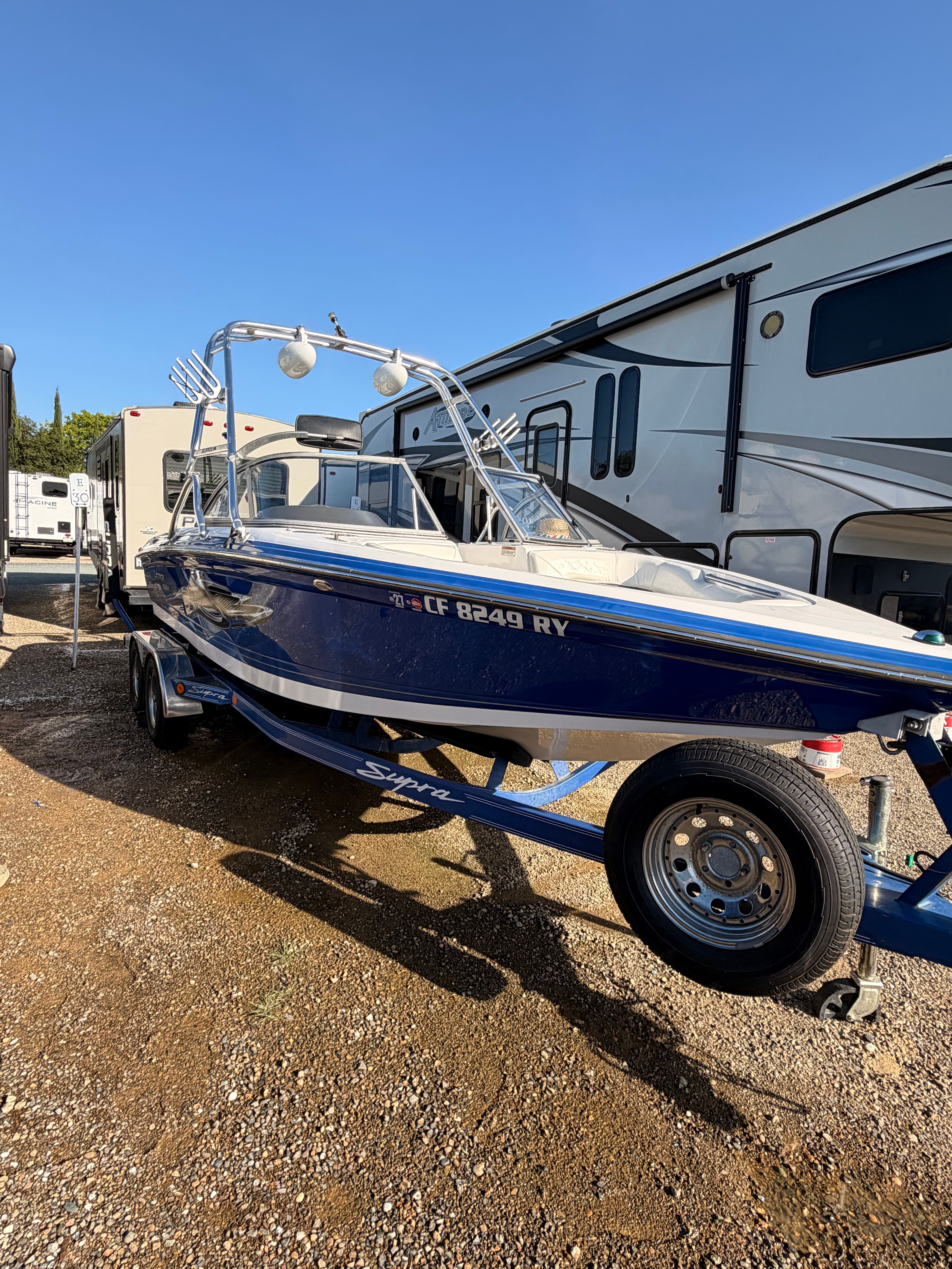 2004 Supra Launch SSV boat on trailer beside RV.