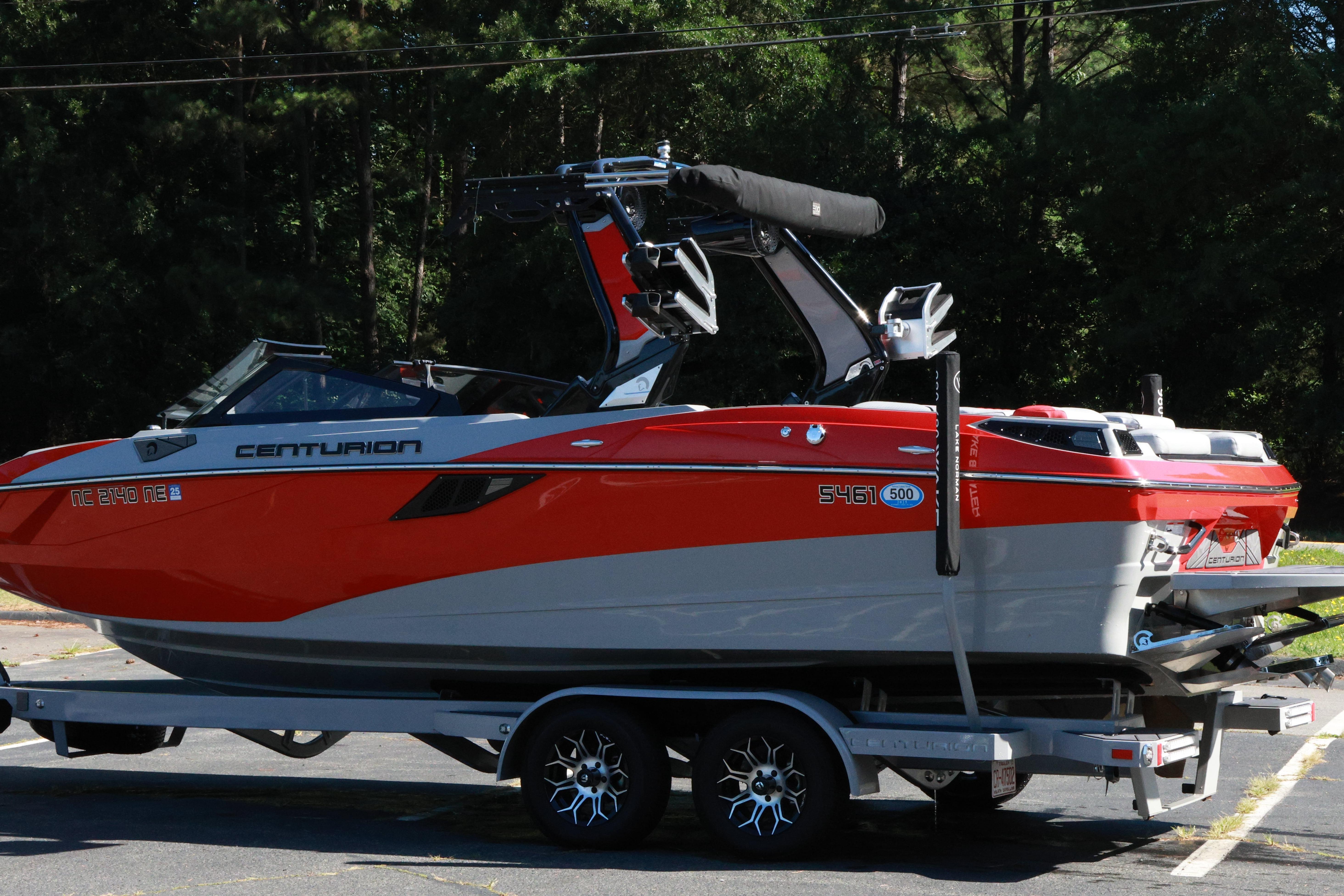 2024 Centurion Fi23 boat in vibrant red and gray on a trailer, parked outdoors.
