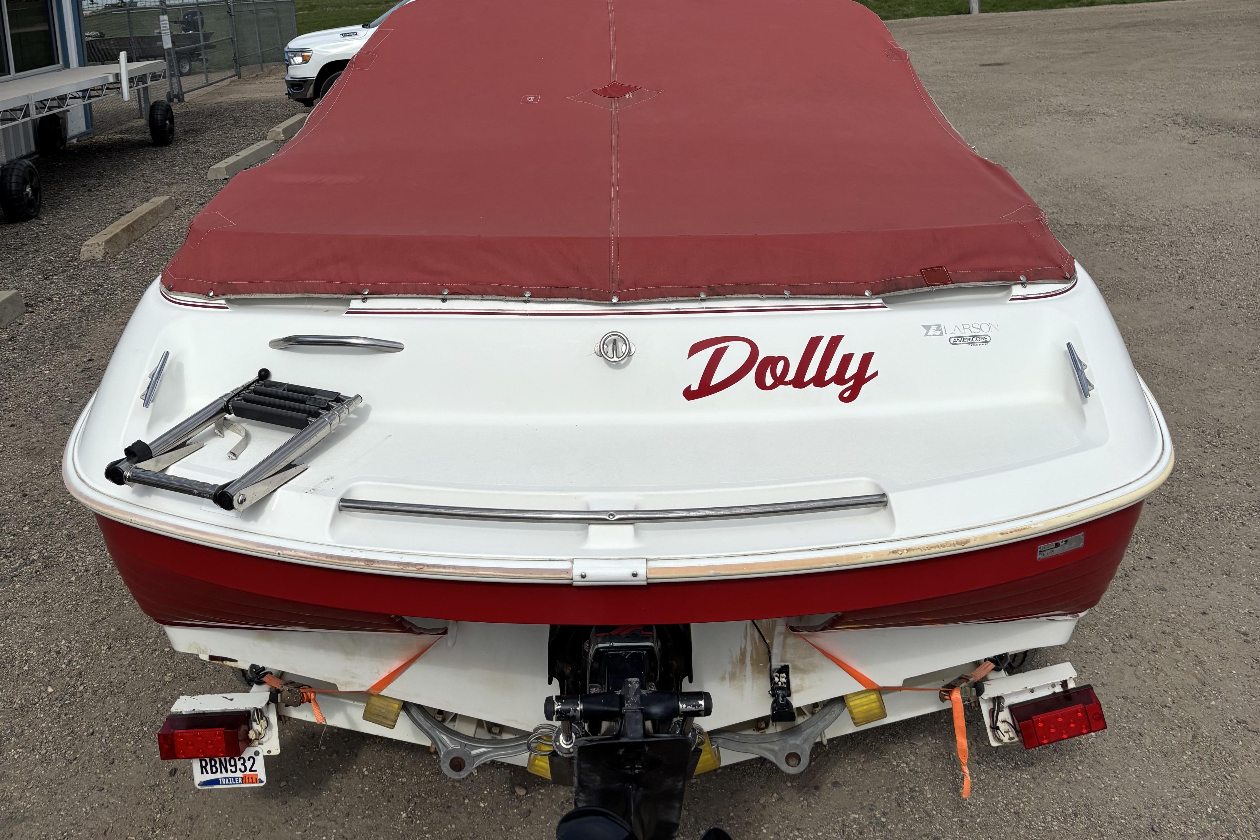 1993 Larson SEi 200 Cuddy I/O boat with red cover, named "Dolly," parked on gravel.