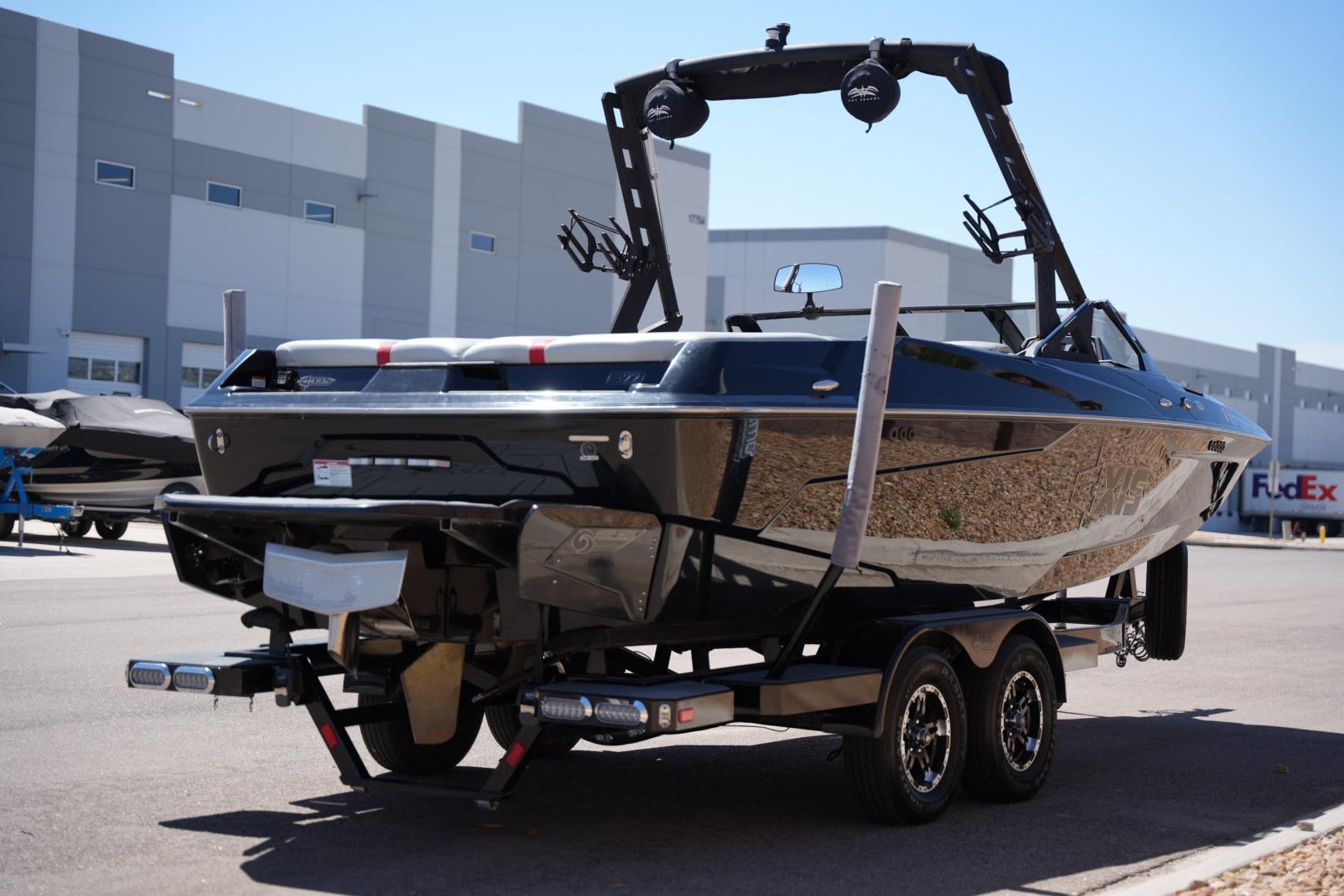 2019 Axis A22 boat on trailer, parked near industrial buildings under clear sky.