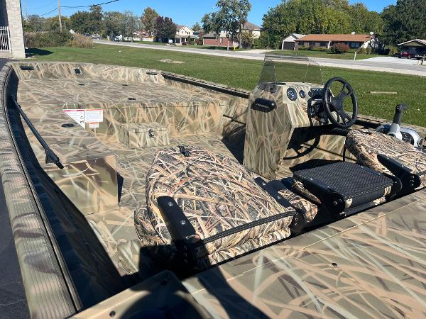 2025 Lowe Roughneck 2070 SC boat with camouflage design, parked outdoors.
