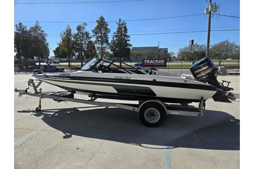 1997 Javelin 389 FS boat on trailer with Johnson outboard motor, parked outdoors.