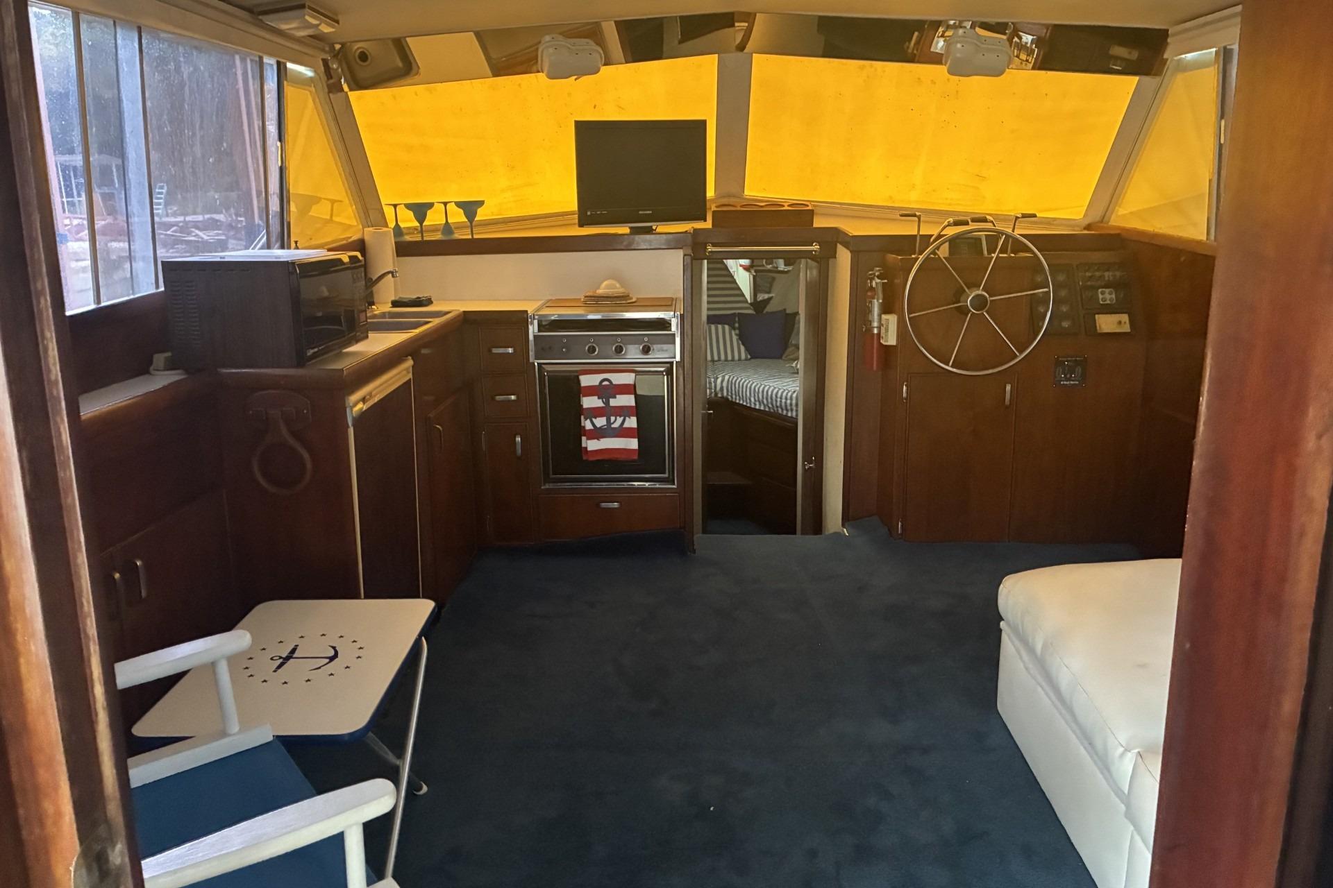 1980 Chris-Craft 360 Commander interior with kitchen, seating, and helm wheel.