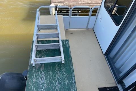 1995 Myacht 40X13 houseboat deck with ladder and railing on calm water.