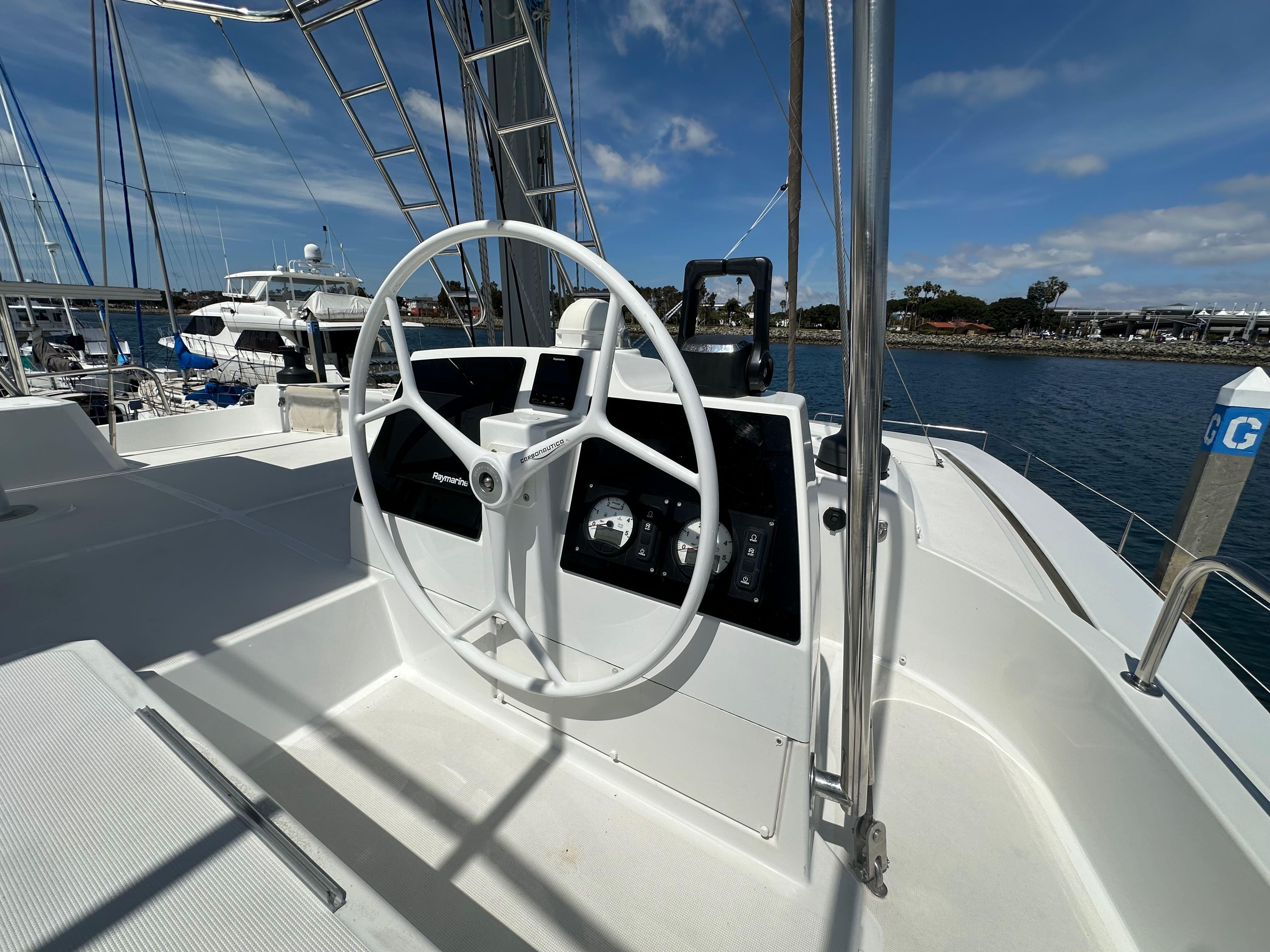Steering wheel of a 2021 Bali 4.8 yacht docked at a marina.