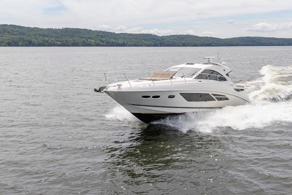2016 Sea Ray Sundancer 510 cruising on a serene lake with lush green hills.