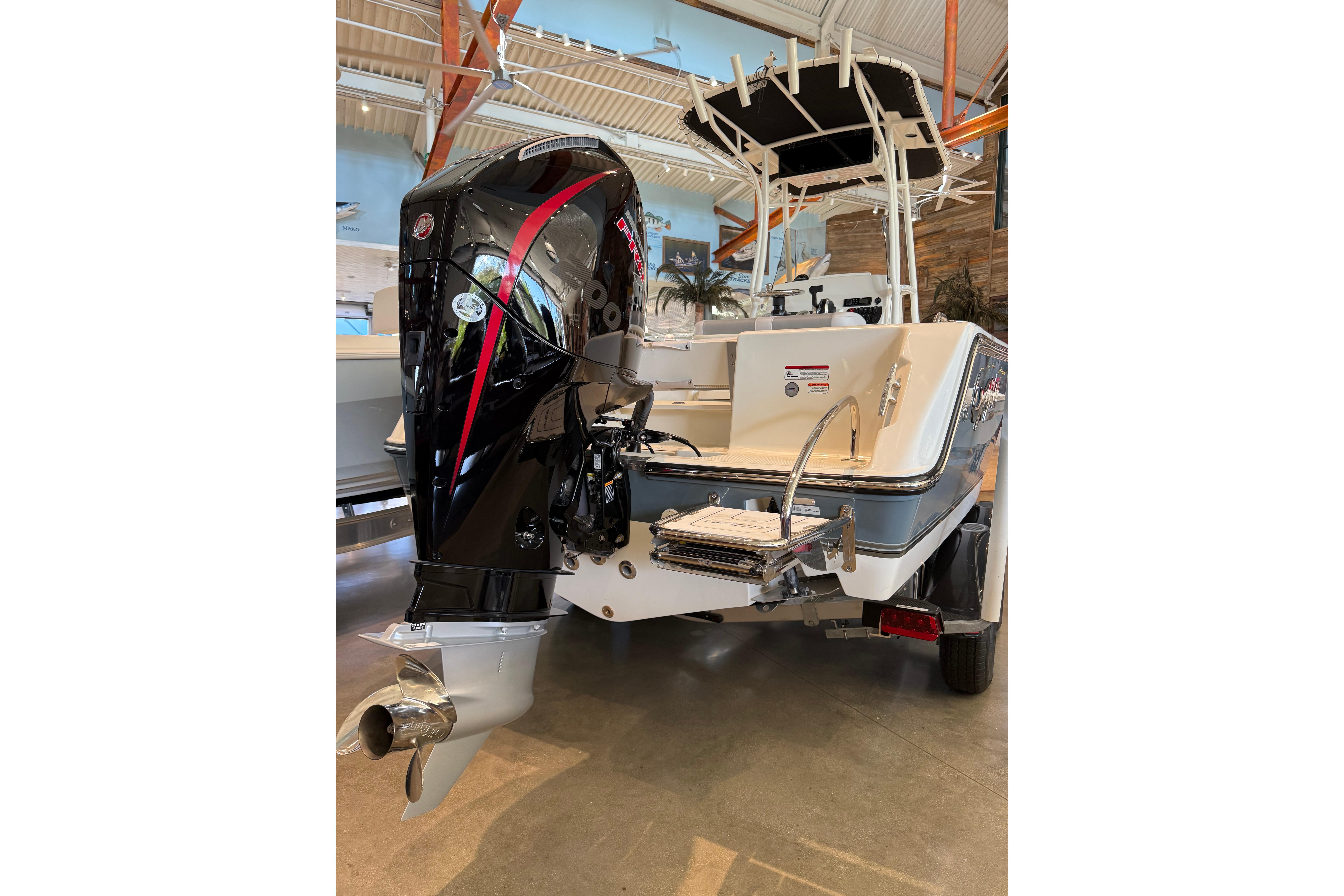 2026 Mako 214 Center Console boat with powerful outboard motor in showroom.