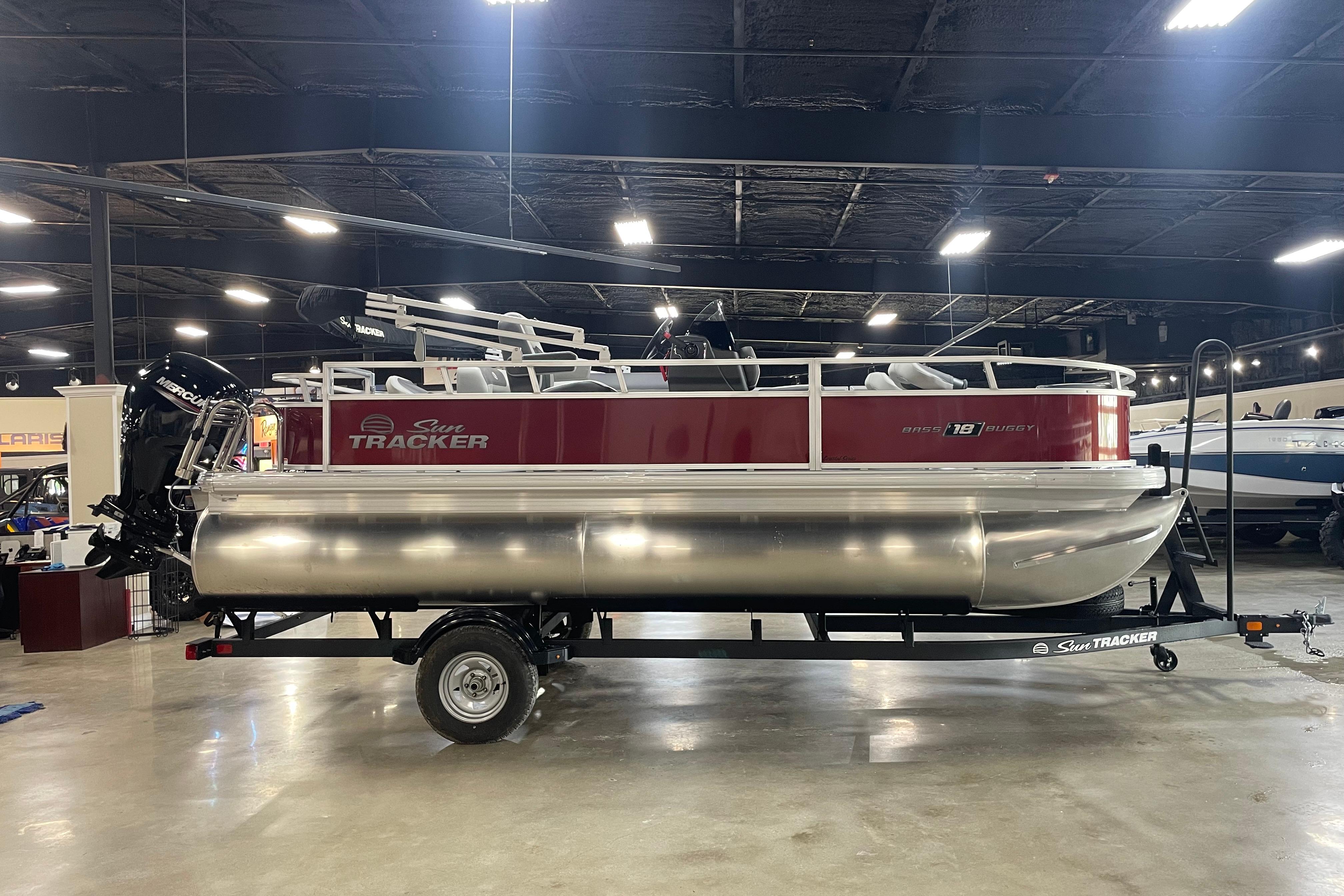 2026 Sun Tracker Bass Buggy 18 DLX pontoon boat displayed indoors on a trailer.