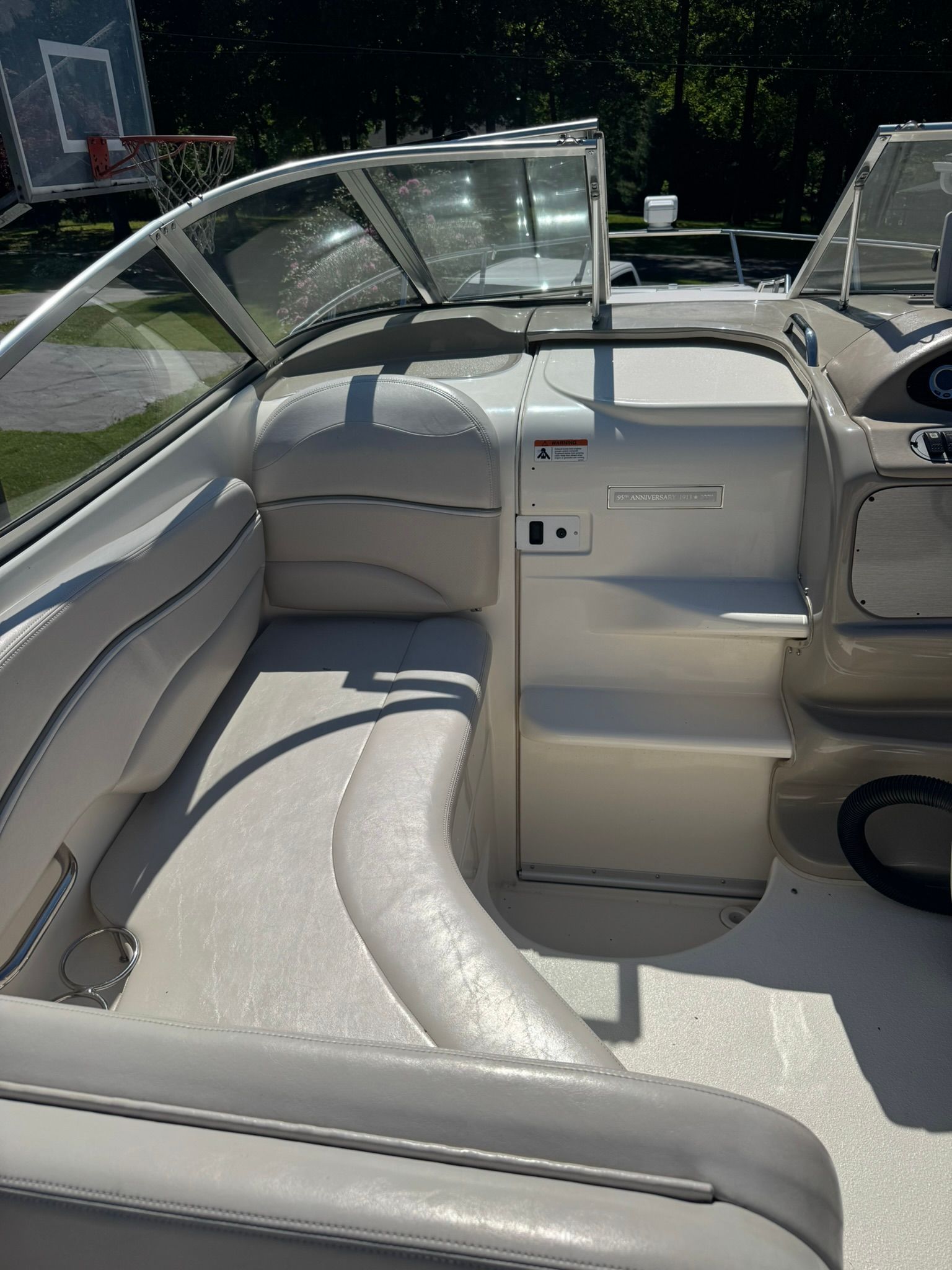 Interior of a white boat with cushioned seating and a control console.